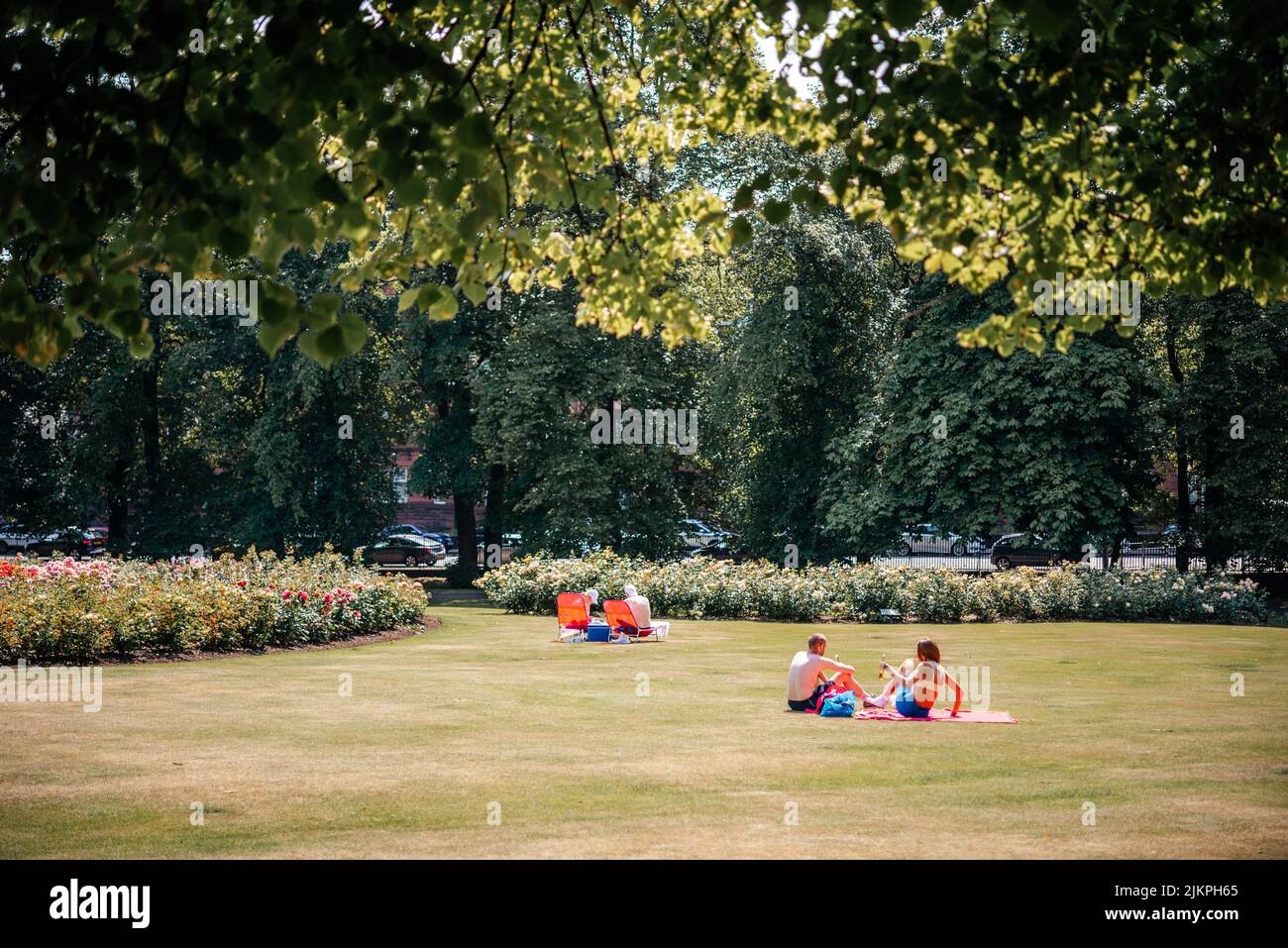 Im Park in Großbritannien sonnen sich die Menschen auf dem Rasen Stockfoto