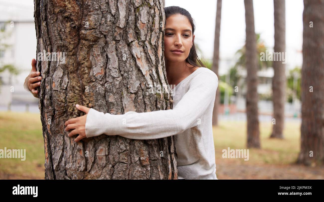 Eine Umarmung mit Jahrhunderten. Ein junges Weibchen umarmt einen Baum in einem Park. Stockfoto
