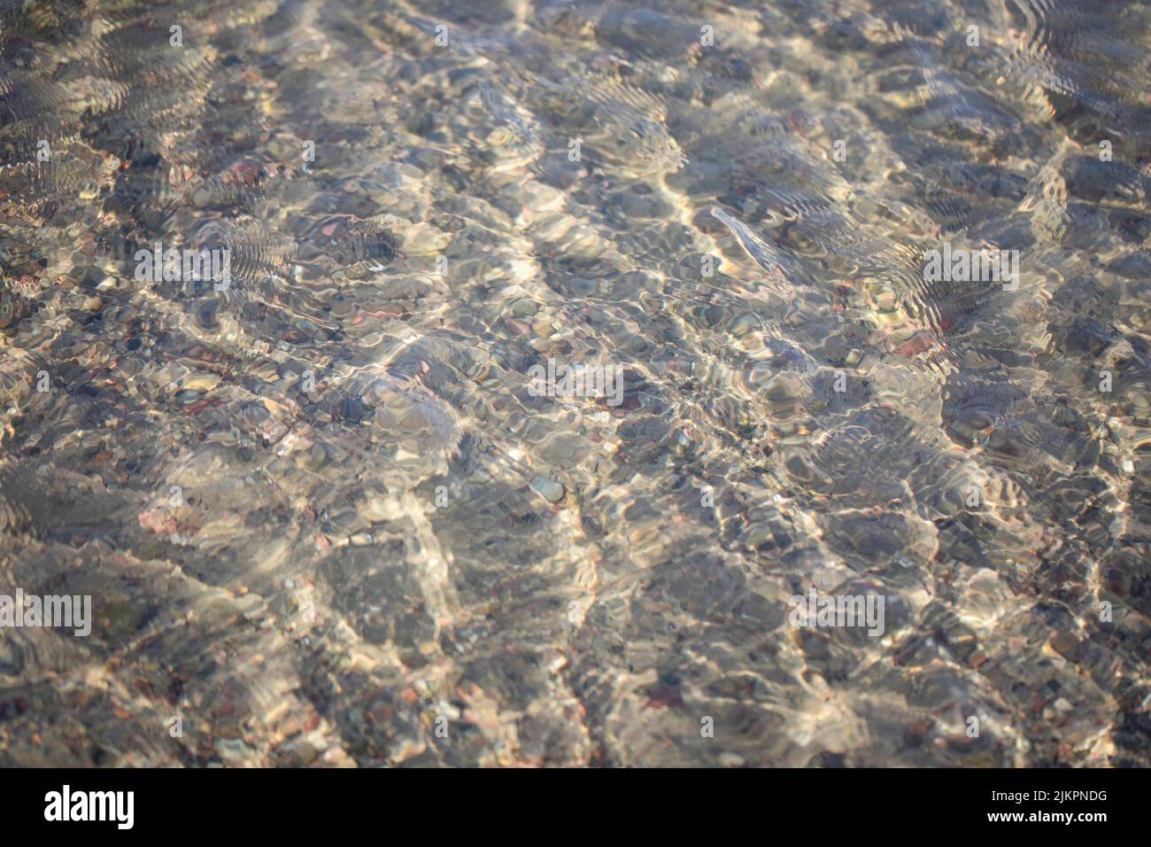 Sonnenreflexe in kristallklaren Gewässern der Ostsee. Wasserstruktur - Wellenmuster, sanfte Windkräusel an der Oberfläche. Stockfoto