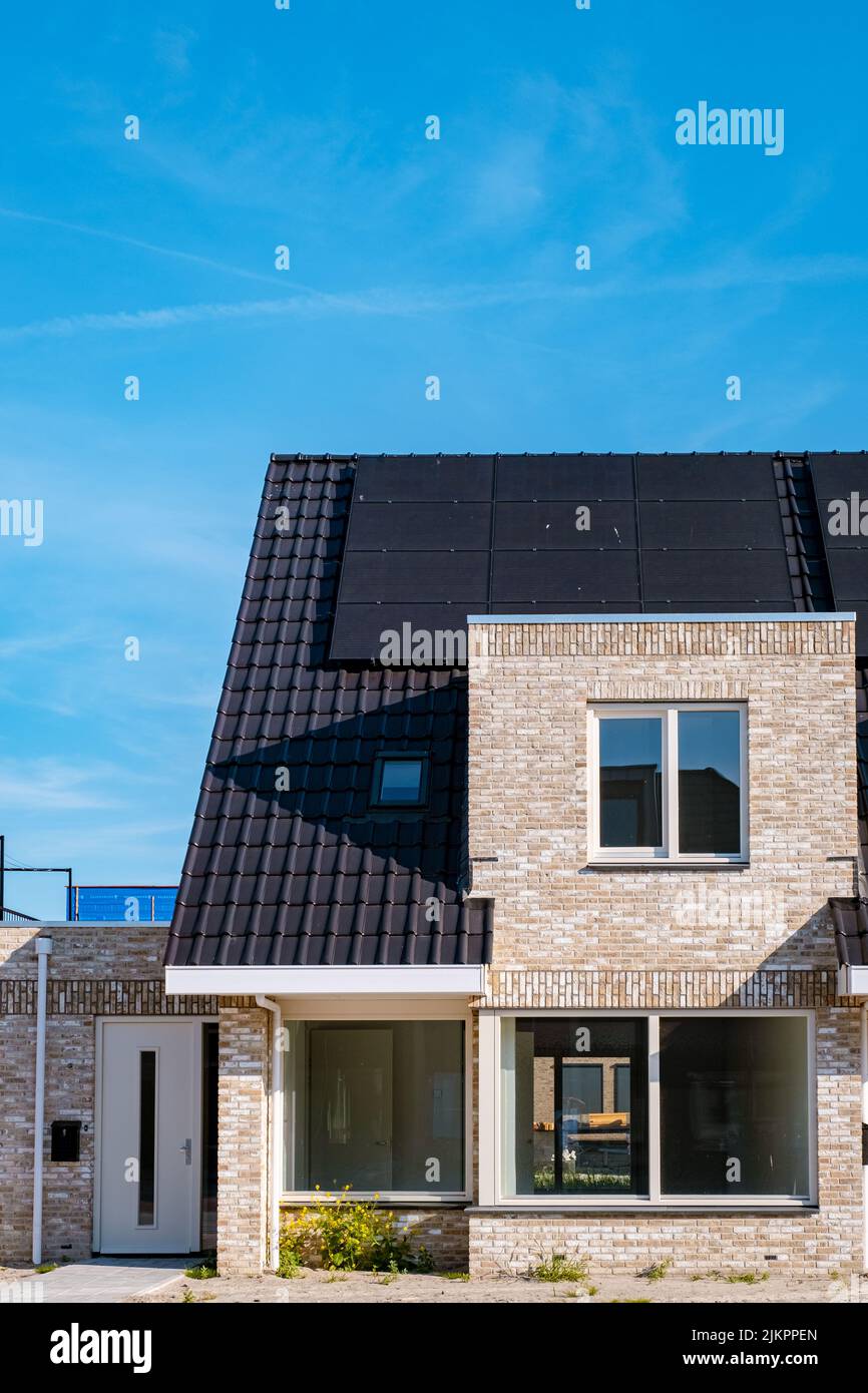 Neubau von Häusern mit Solarpaneelen auf dem Dach vor einem sonnigen Himmel Nahaufnahme eines neuen Gebäudes mit schwarzen Solarpaneelen. Zonnepanelen, Zonne energie, Übersetzung: Sonnenkollektoren, , Sonnenenergie. Stockfoto