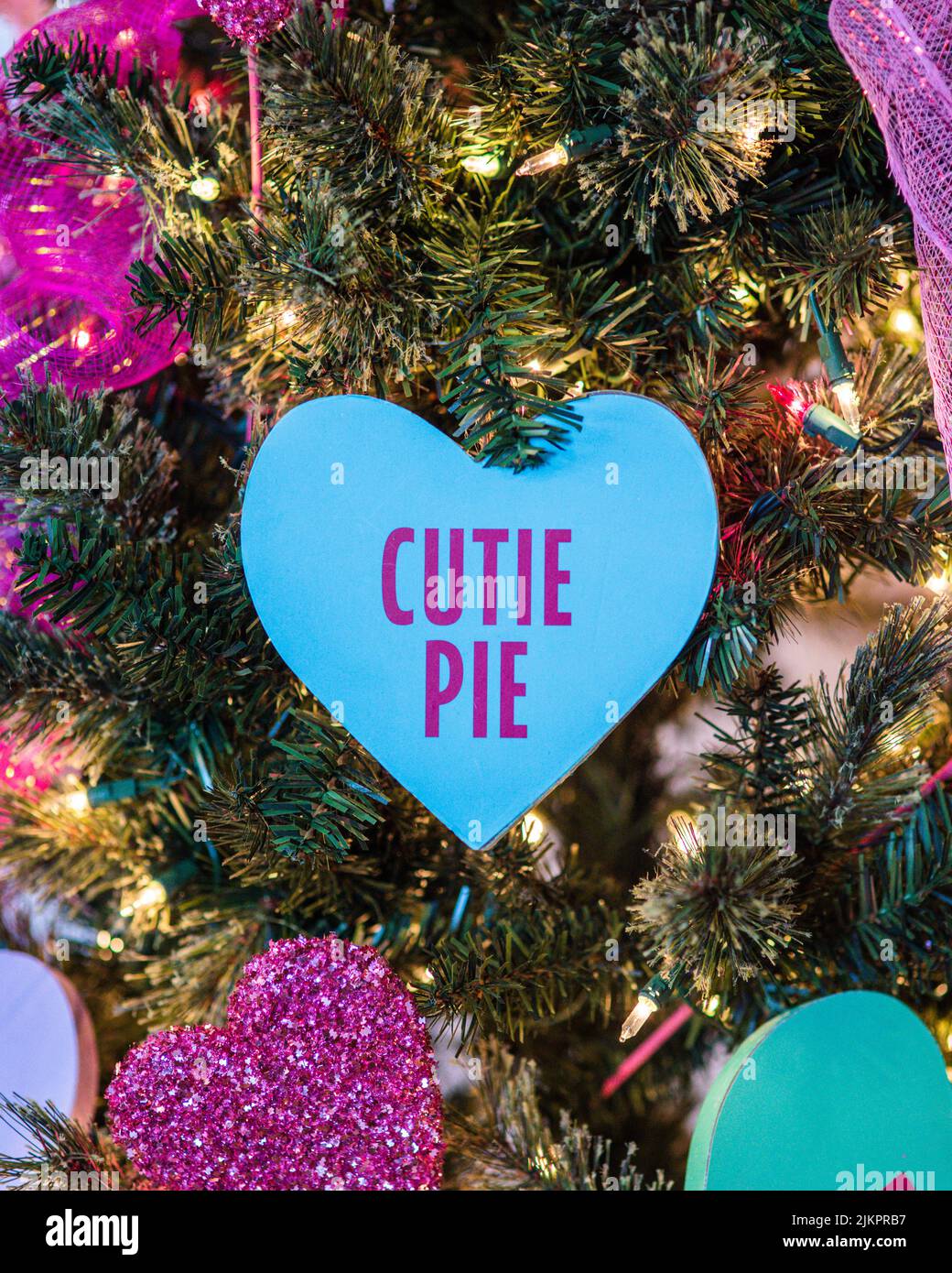 Eine vertikale Nahaufnahme einer blauen Cutie-Pie-Karte auf einem Weihnachtsbaum Stockfoto