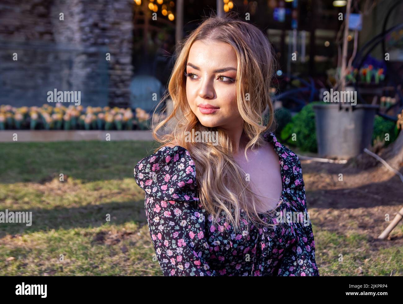 Eine schöne junge kaukasische Frau, die ein Blumenkleid trägt, das im Freien posiert Stockfoto