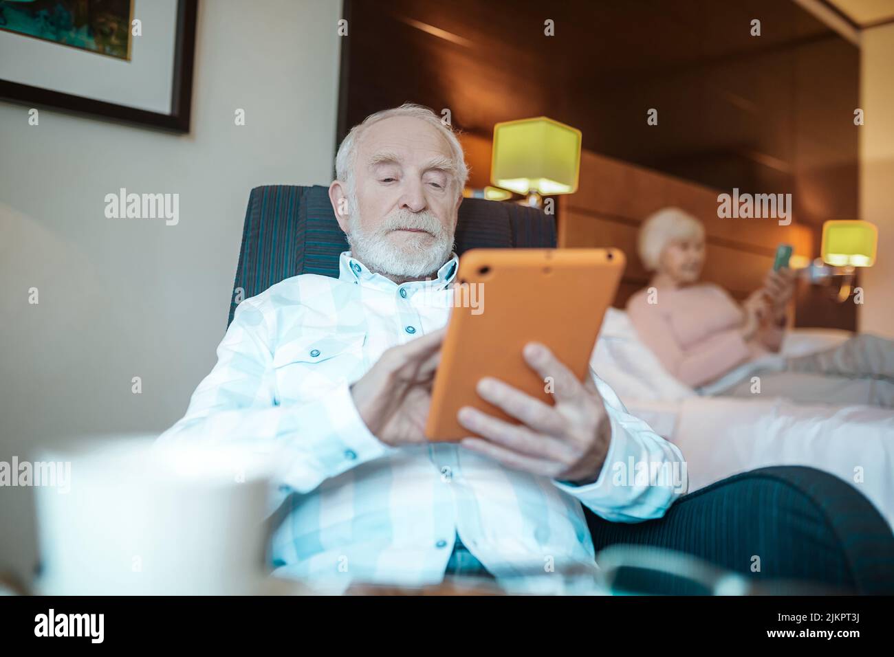 Grau angeheuerten bärtigen Mann mit Tablet in den Händen schauen nachdenklich Stockfoto