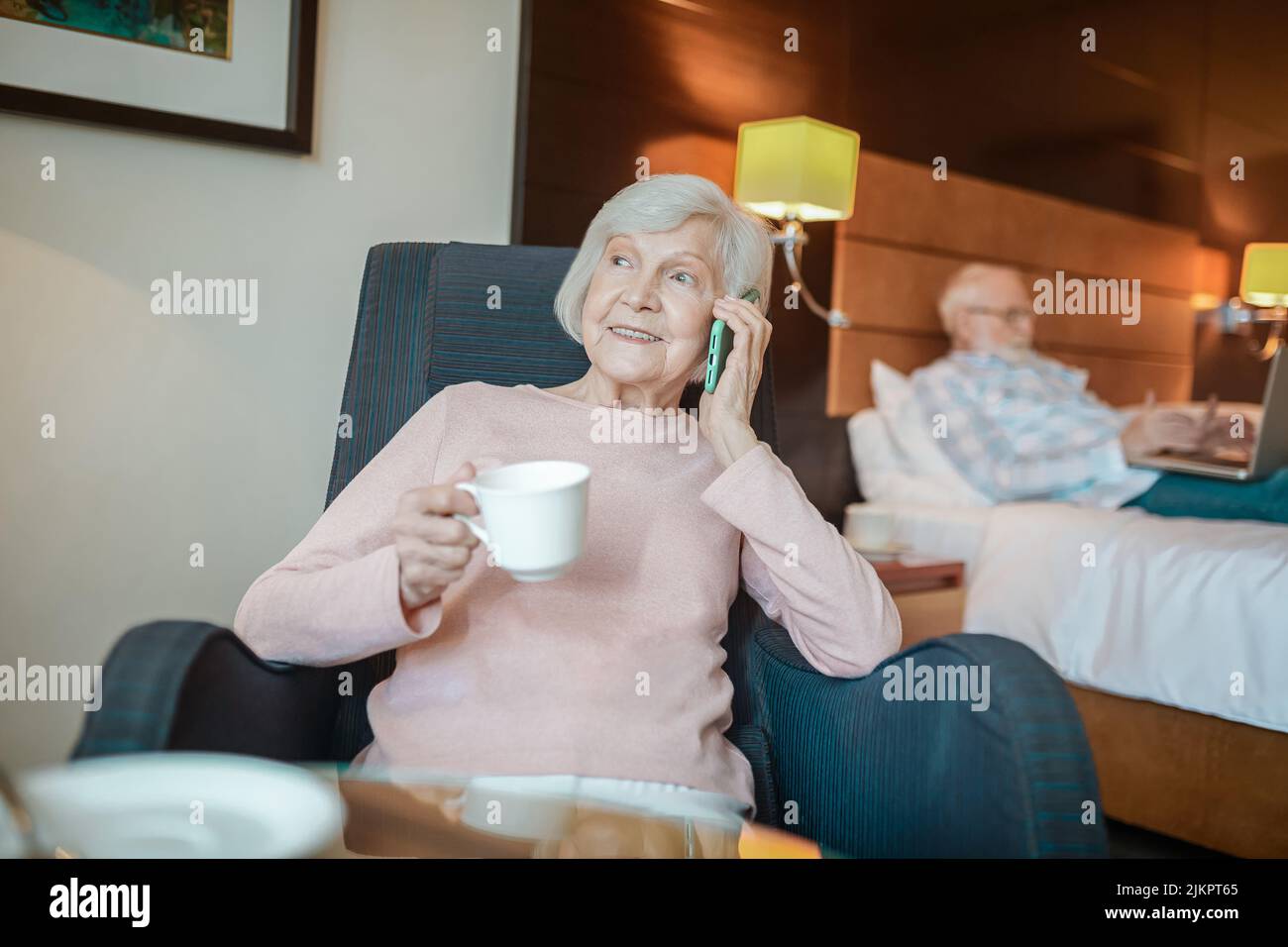 Ältere gut aussehende Dame mit Kaffee und hoding ein Smartphone in den Händen Stockfoto