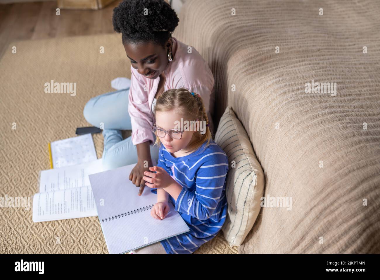 Ein Mädchen mit Down-Syndrom, das mit ihrem Lehrer etwas liest Stockfoto