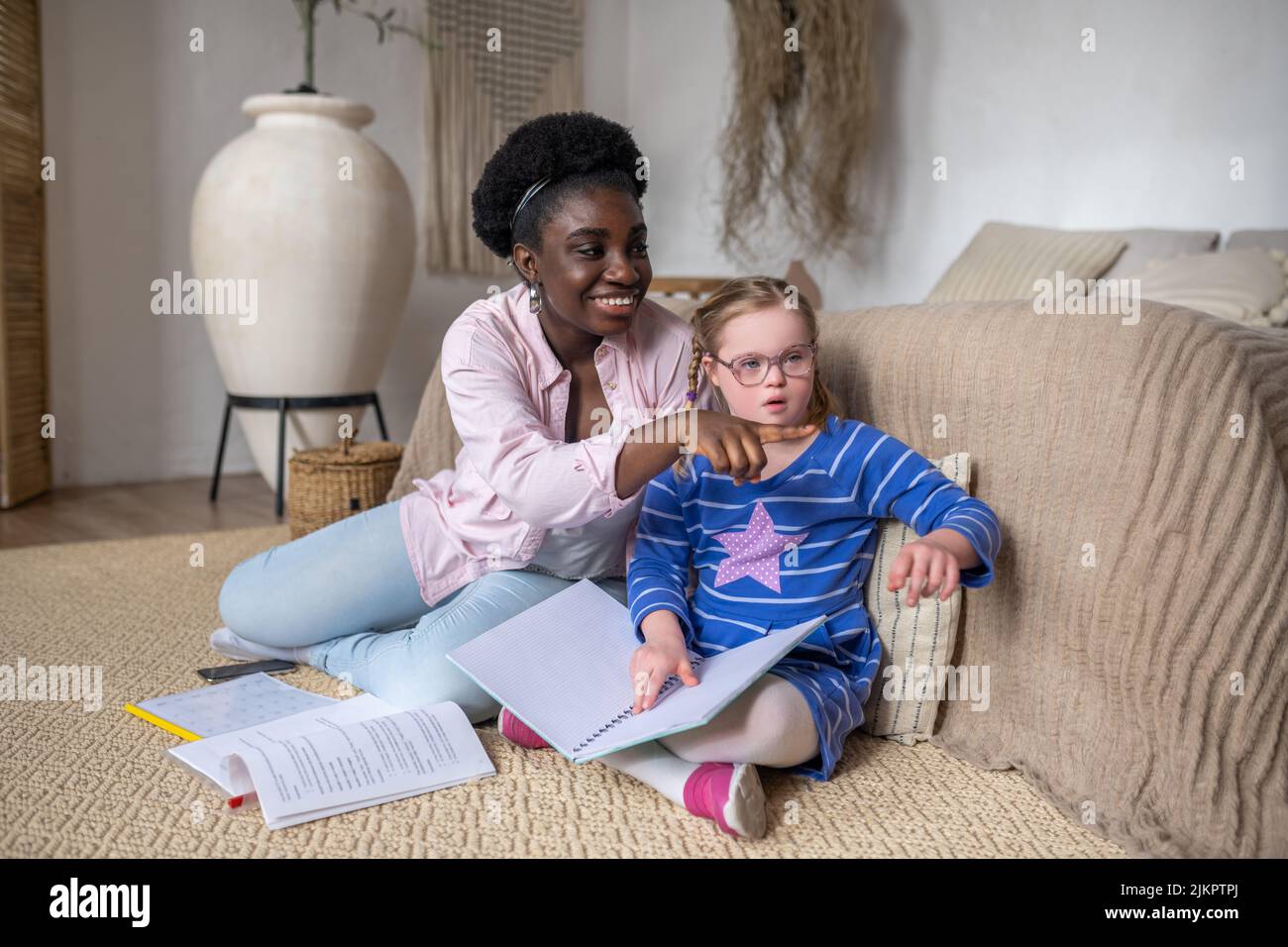 Ein Mädchen mit Down-Syndrom, das mit ihrem Lehrer etwas liest Stockfoto
