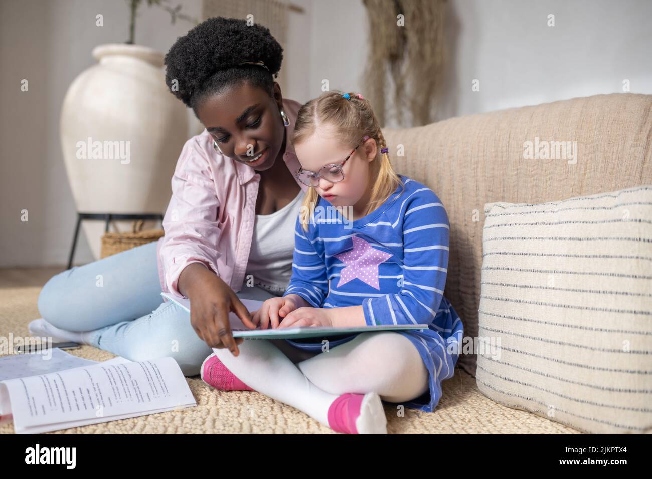 Ein Mädchen mit Down-Syndrom, das mit ihrem Lehrer etwas liest Stockfoto