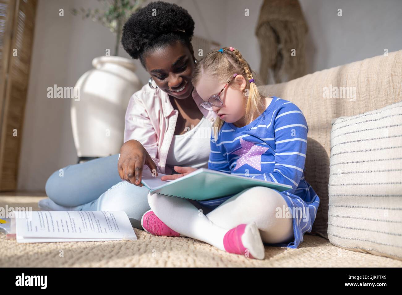 Ein Mädchen mit Down-Syndrom, das mit ihrem Lehrer etwas liest Stockfoto