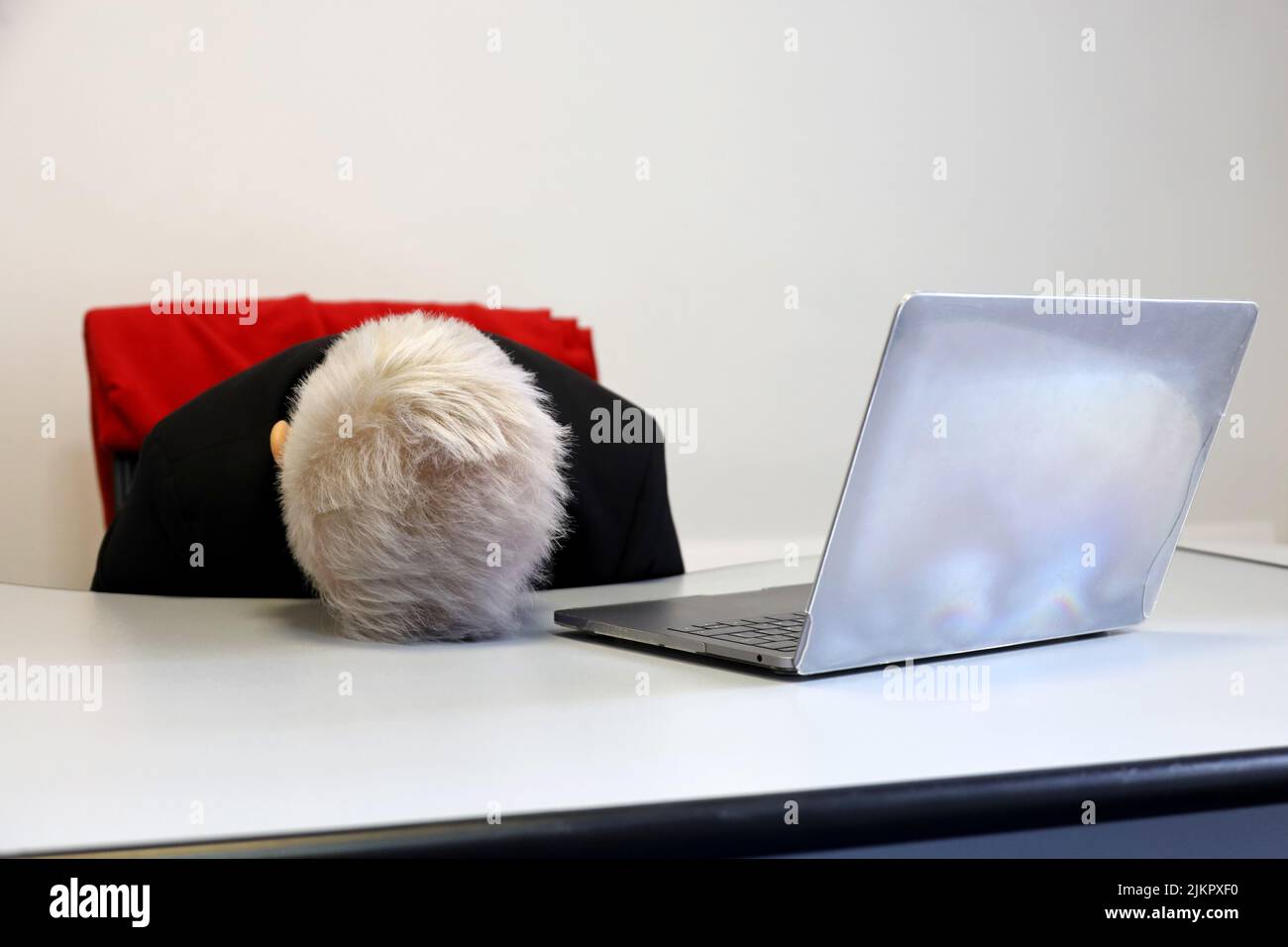 Frau mit kurzgefärbten Haaren schläft in der Nähe des Laptops am Bürotisch. Konzept eines überarbeiteten Mitarbeiters, müde nach der Arbeit, fauler Tag Stockfoto
