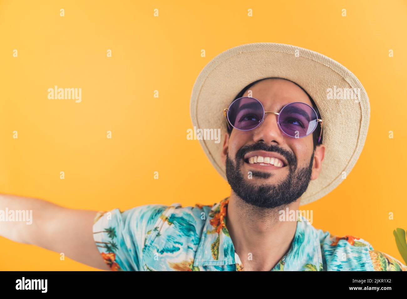 Hispanischer bärtiger Tourist mit Hut und Sonnenbrille freute sich auf den Urlaub und schaute nach oben. Weit gestreckte Arme lächeln. Studioaufnahme. Hochwertige Fotos Stockfoto