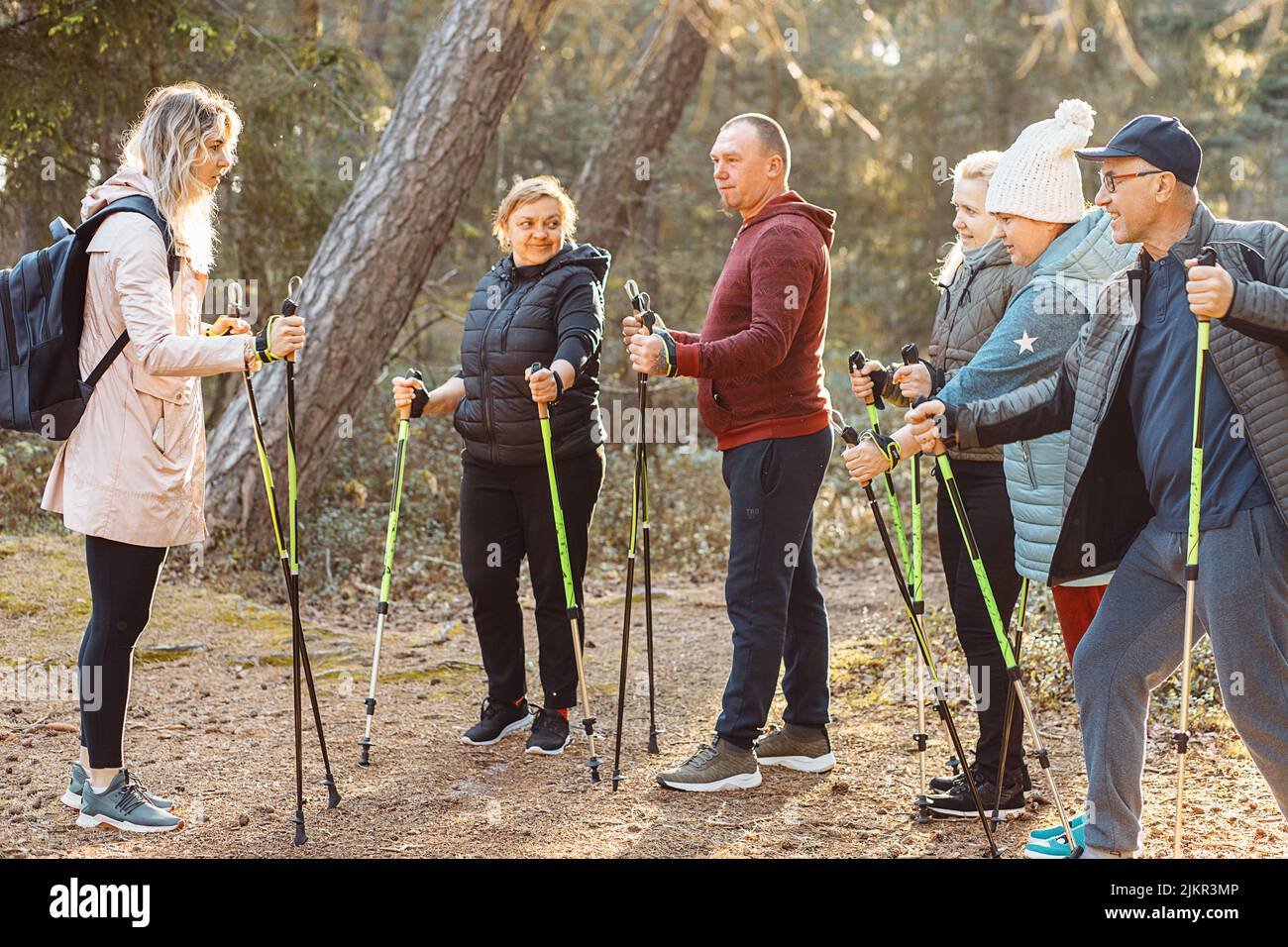 Professionelle Trainerin, Trainerin mit Gruppenmitarbeiten unterrichten skandinavisches, Nordic Walking mit Stöcken im Wald Stockfoto