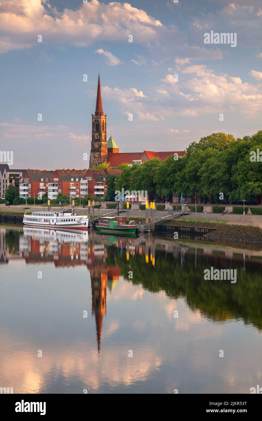 Bremen, Deutschland. Stadtbild des Bremer Flussufers mit Spiegelung der Stephani-Kirche in der Weser bei Sommersonnenaufgang. Stockfoto