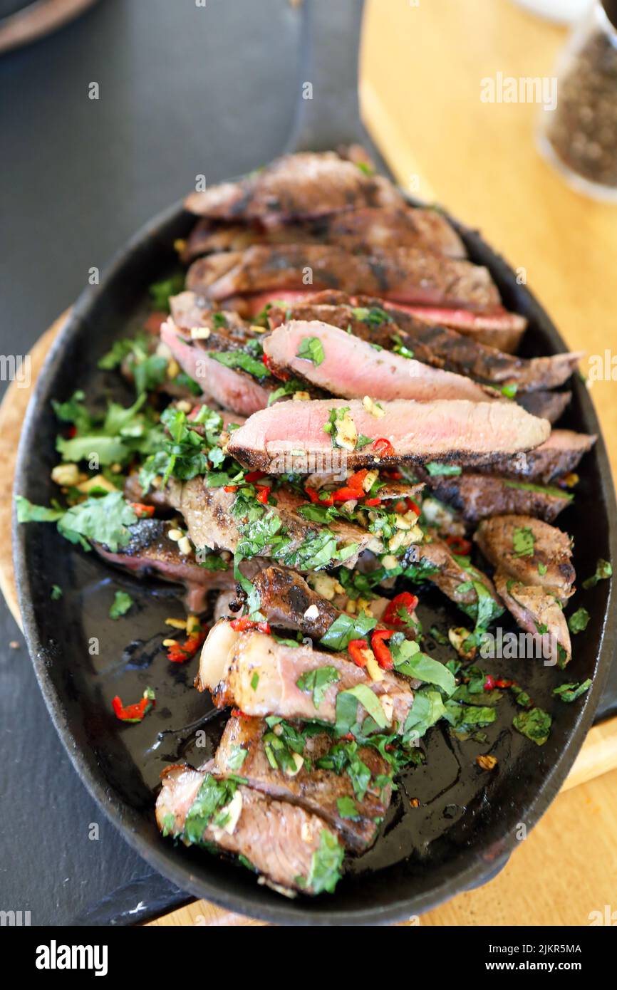 Ribeye Steak in Scheiben mit Koriander, Knoblauch und Chilis in einer heißen Pfanne Stockfoto