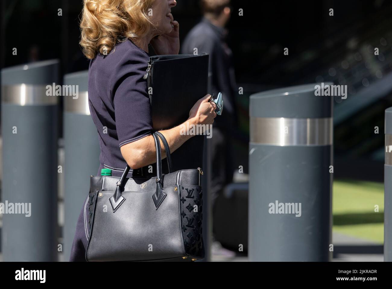 Geschäftsfrau, die während eines geschäftlichen Anrufs durch die City of London geht, London, Großbritannien Stockfoto