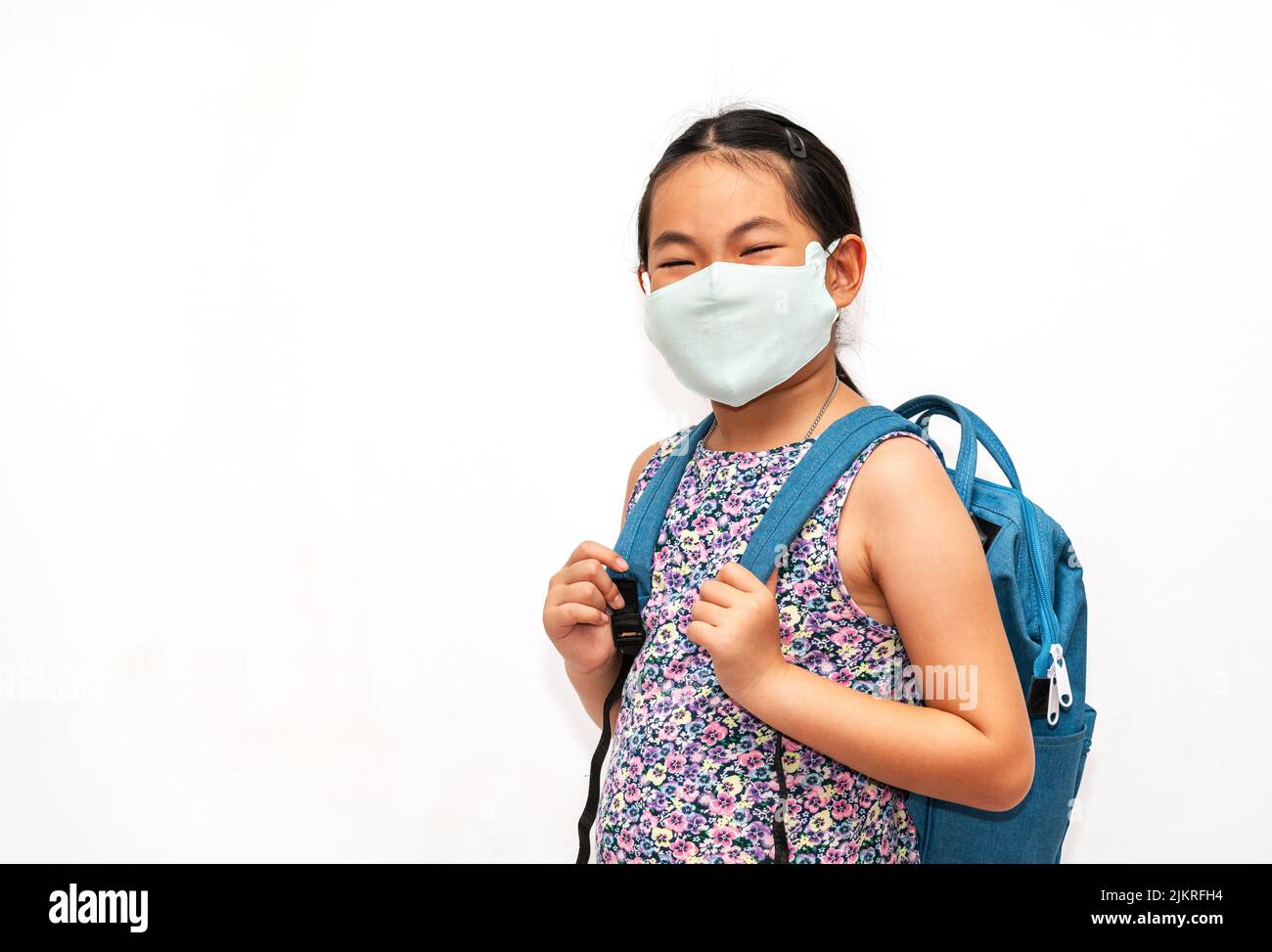Portrait glücklich asiatische Kind Mädchen mit Gesichtsmask, mit Rucksack zur Schule zu gehen, asiatische Schüler Kind im Alter von 7 bis 9 Jahren, isoliert Porträt auf Stockfoto