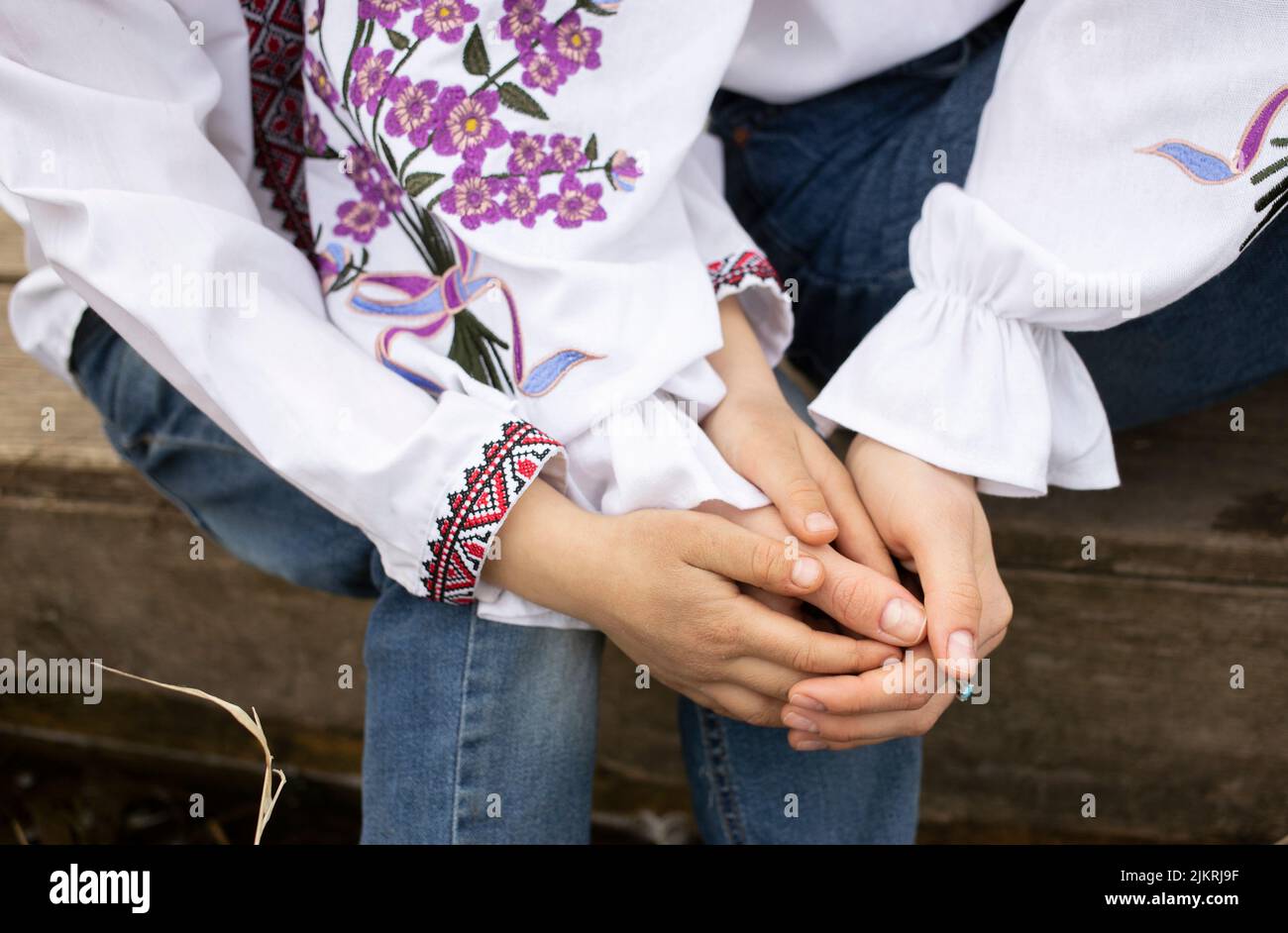 Kinder- und Frauenhände in bestickter ukrainischer Kleidung, halten sich gegenseitig. Konzept der Nation, Einheit, Familienunterstützung, Zärtlichkeit, Sicherheit. Humani Stockfoto