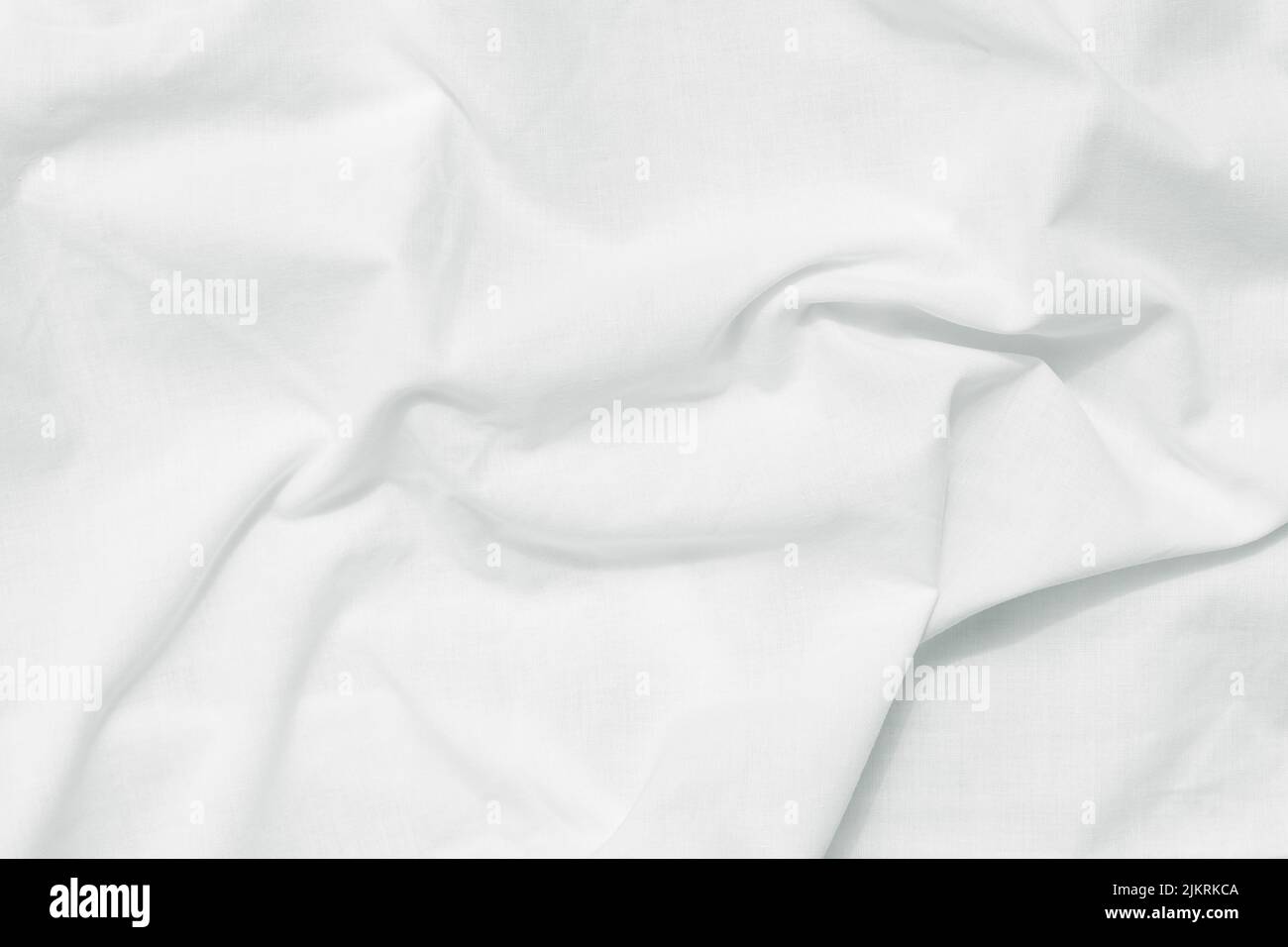 Weißer gekrümmter Bettlaken-Hintergrund, Draufsicht. Naturstoff-Muster, Faltenstruktur. Oberfläche von knitterarbigen Baumwolltextilien. Leerer Raum Stockfoto