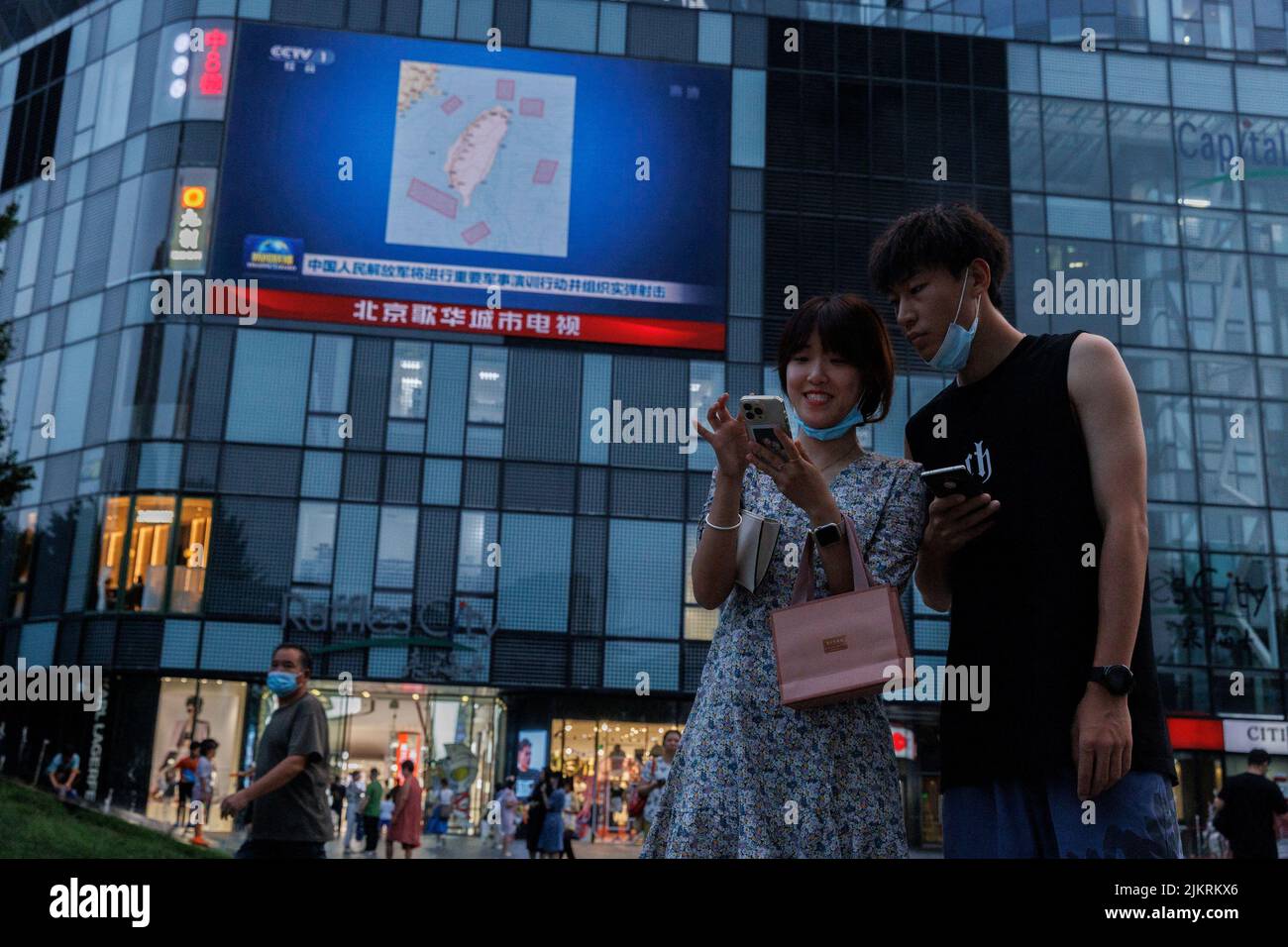Menschen stehen vor einem Bildschirm, auf dem eine CCTV-Nachrichtenübertragung gezeigt wird, auf der eine Karte mit Orten in Taiwan zu sehen ist, an denen die chinesische Volksbefreiungsarmee (PLA) in einem Einkaufszentrum in Peking, China, militärische Übungen und Trainingsaktivitäten einschließlich Live-Feuerübungen durchführen wird, 3. August 2022. REUTERS/Thomas Peter TPX-BILDER DES TAGES Stockfoto