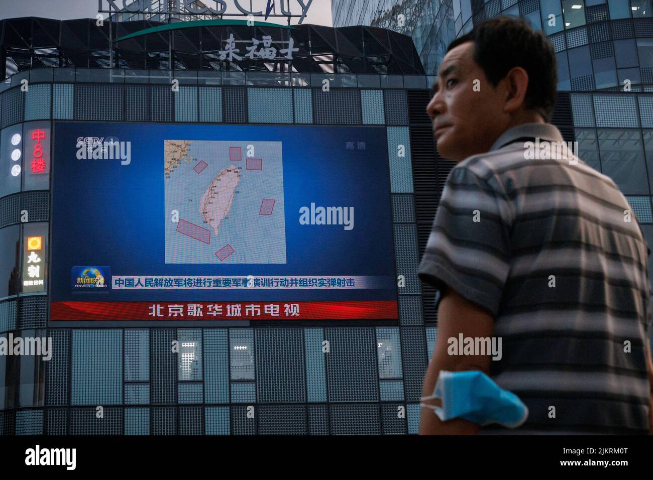 Ein Mann steht vor einem Bildschirm, auf dem eine CCTV-Nachrichtenübertragung gezeigt wird, auf der eine Karte der Orte in Taiwan zu sehen ist, an denen die chinesische Volksbefreiungsarmee (PLA) in einem Einkaufszentrum in Peking, China, militärische Übungen und Trainingsaktivitäten einschließlich Live-Feuerübungen durchführen wird, 3. August 2022. REUTERS/Thomas Peter Stockfoto