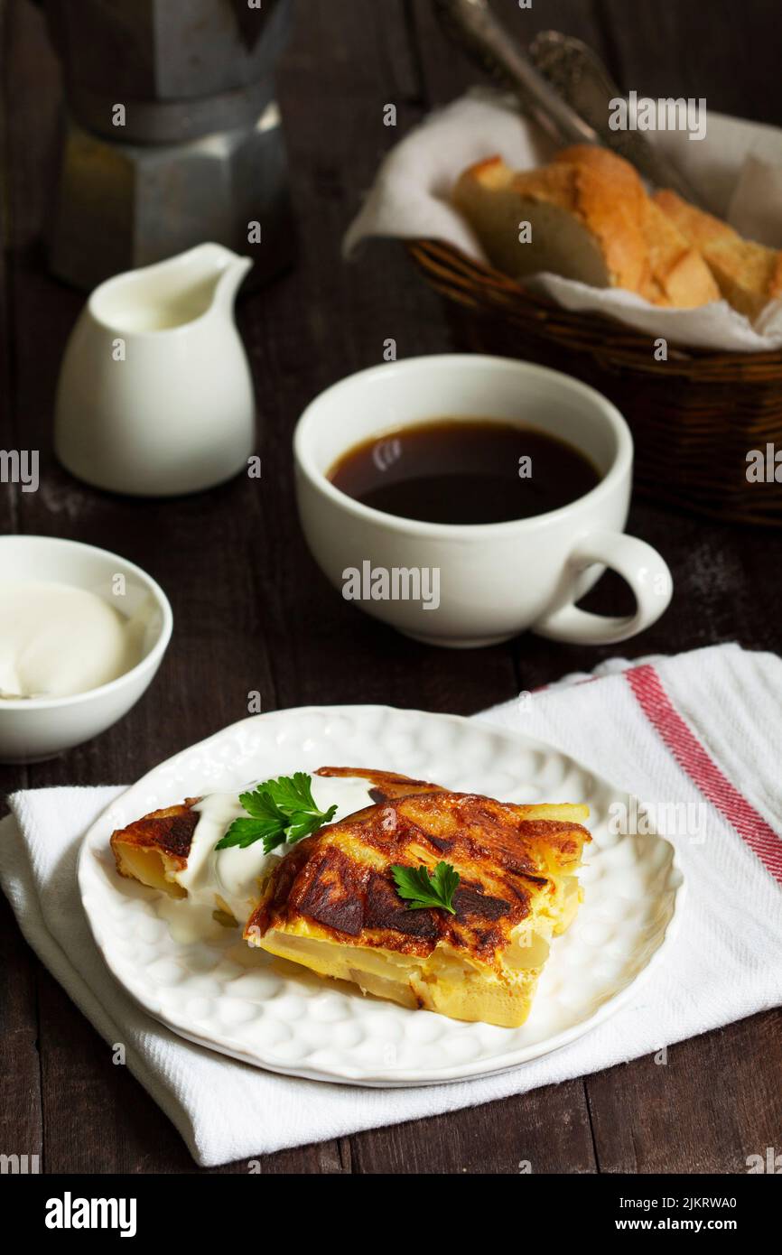 Traditionelles spanisches oder italienisches Omelett mit Kartoffeln, serviert mit Kaffee. Rustikaler Stil. Stockfoto