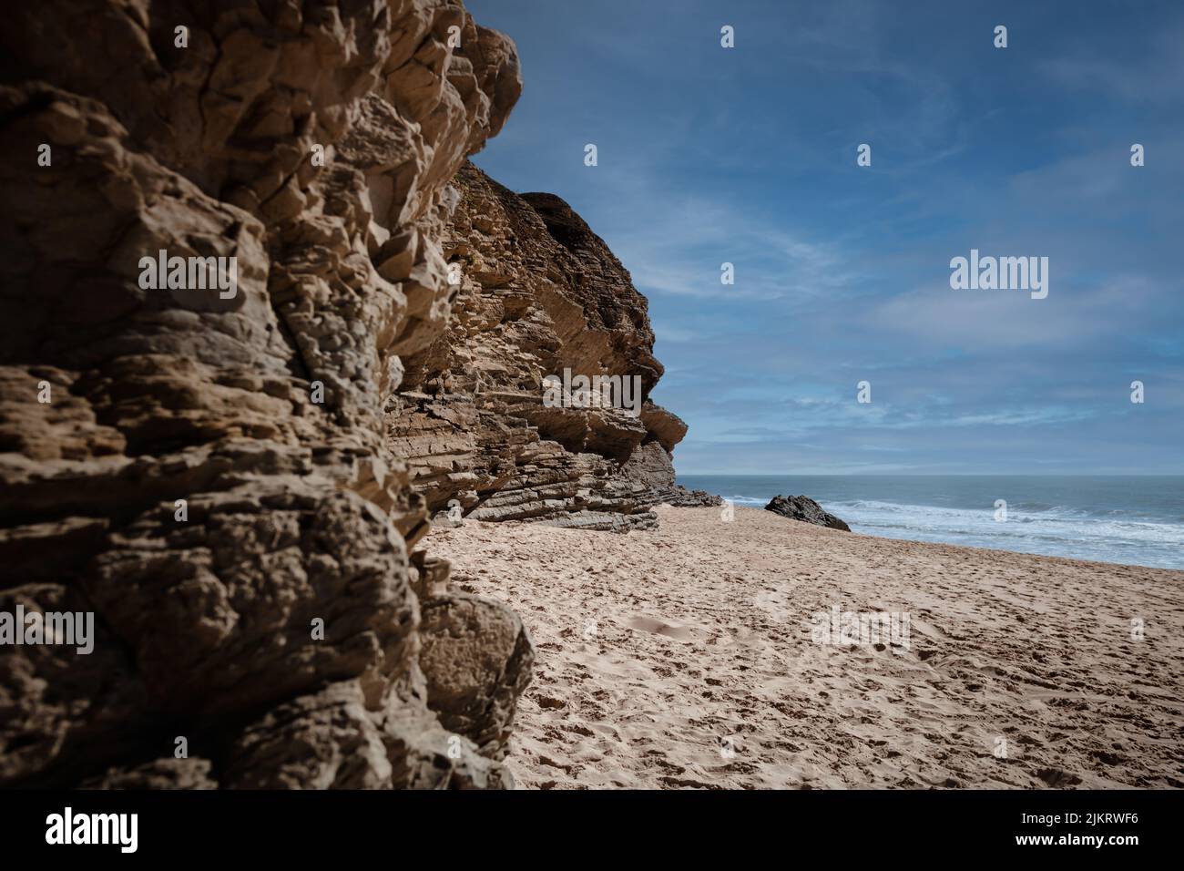 Praia da Murtinheira in Quiaios, Portugal, ein ruhiger und wilder Strand abseits der Menschenmassen. Nahaufnahme von felsigen Küsten, Sand und blauem Himmel. Foto im Landscape-Bild Stockfoto