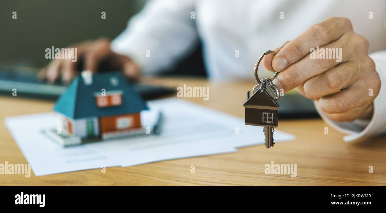 Immobilienmakler, der dem Kunden neue Hausschlüssel gibt, nachdem der Vertrag abgeschlossen ist. Banner mit Kopierraum Stockfoto