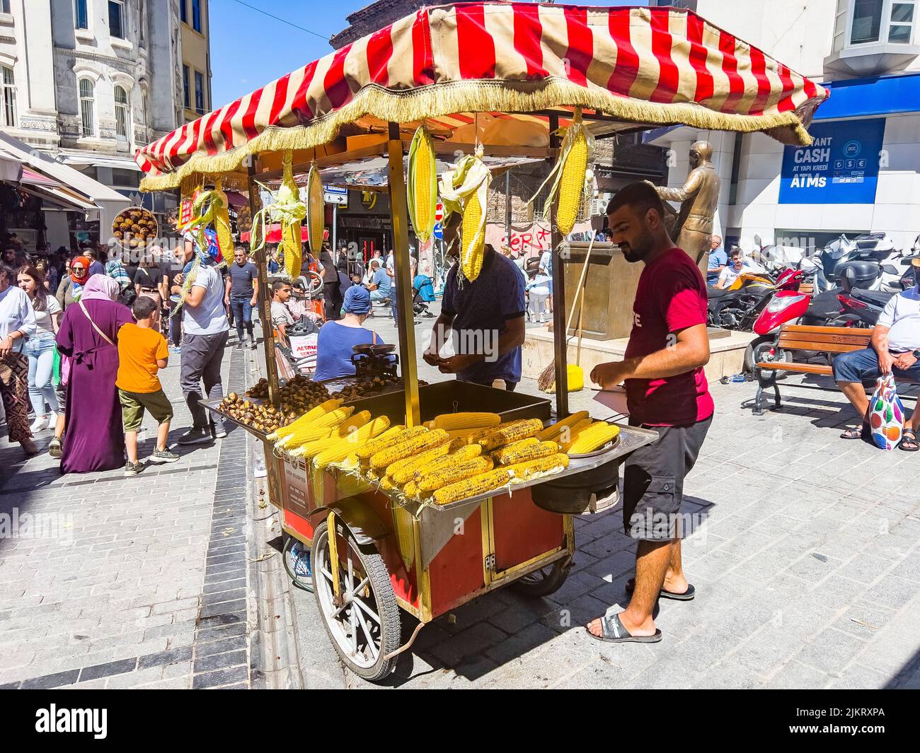 Istanbul, Türkei, 07.14.2022: Mann, der gegrillten Mais verkauft. Street Verkäufer von Fast Food mit gekochtem, gegrilltem Mais und Kastanien auf traditionellen türkischen Karren Stockfoto