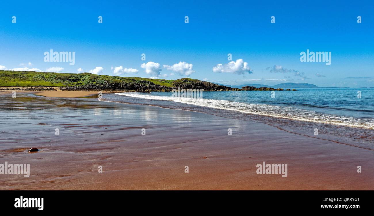 RED POINT STRAND ROSS UND CROMARTY SCHOTTLAND BLAUES MEER UND HIMMEL UND DER ROTE SAND VON WELLEN GEWASCHEN Stockfoto