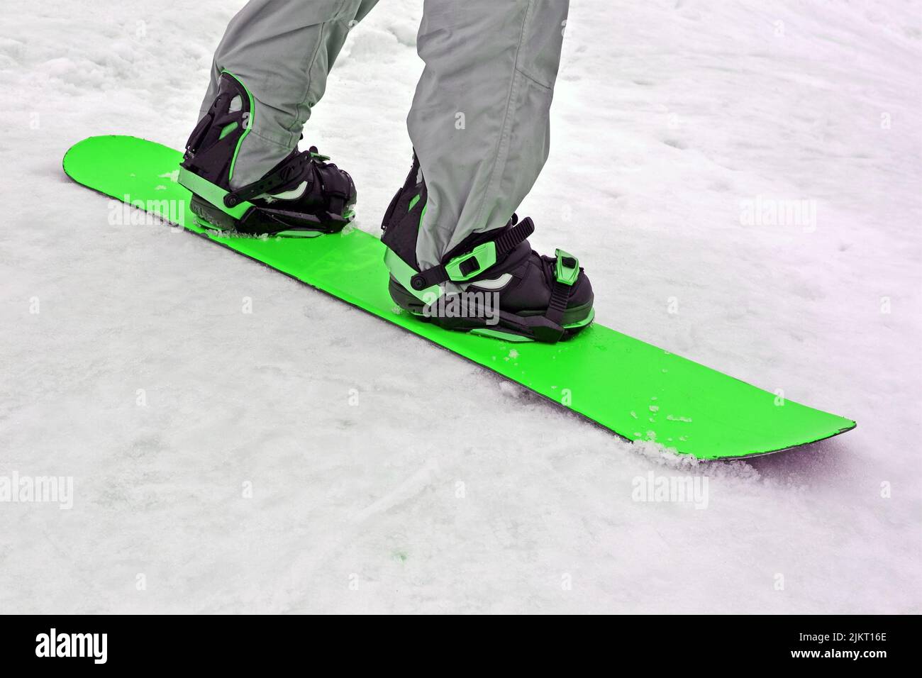 Sportler mit grünem Snowboard auf weißem Schnee, saisonale Sportvielfalt Stockfoto