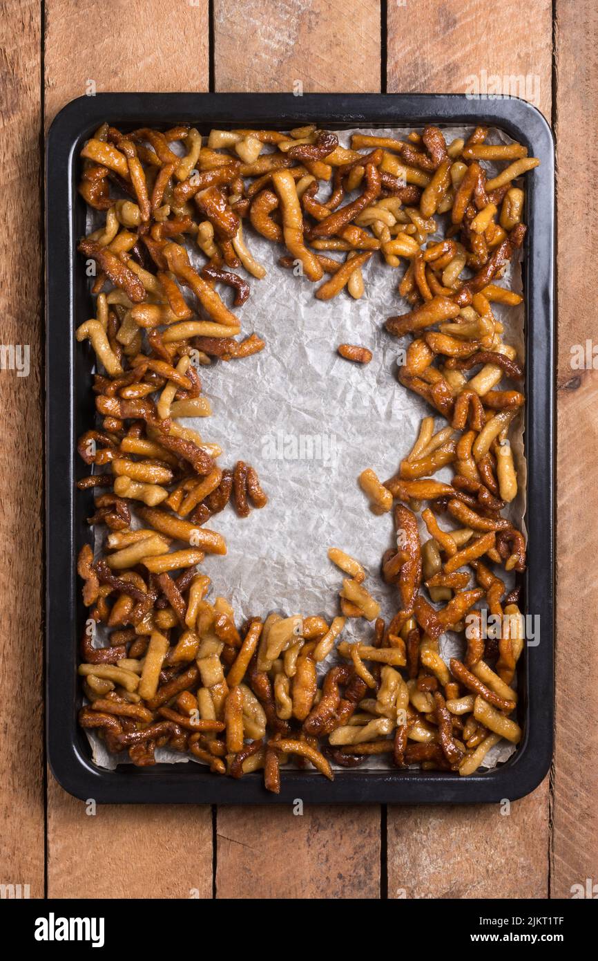Frisch zubereiteter herzhafter und knackiger Snack, überzogen mit Zuckersirup auf schwarzem Tablett, traditioneller und beliebter indischer süßer Murukku, direkt von oben entnommen Stockfoto