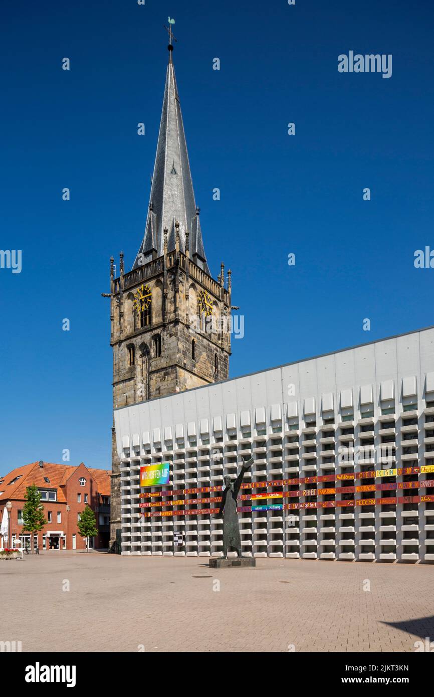 Deutschland, Ahaus, Westmuensterland, Münsterland, Westfalen, Nordrhein-Westfalen, NRW, Katholische Mariä Himmelfahrt-Kirche auf dem Marktplatz stammt der Kirchturm aus der historischen Kirche und das Kirchenschiff wurde von Erwin Schiffer als Betonbau befestigt, vor der Skulptur 'der Mahner' von Hilde Schuerk frisch Stockfoto