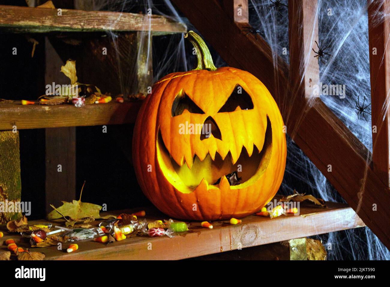 jack-o-Laternenkürbis und verstreute Halloween-Süßigkeiten auf der Veranda Stockfoto