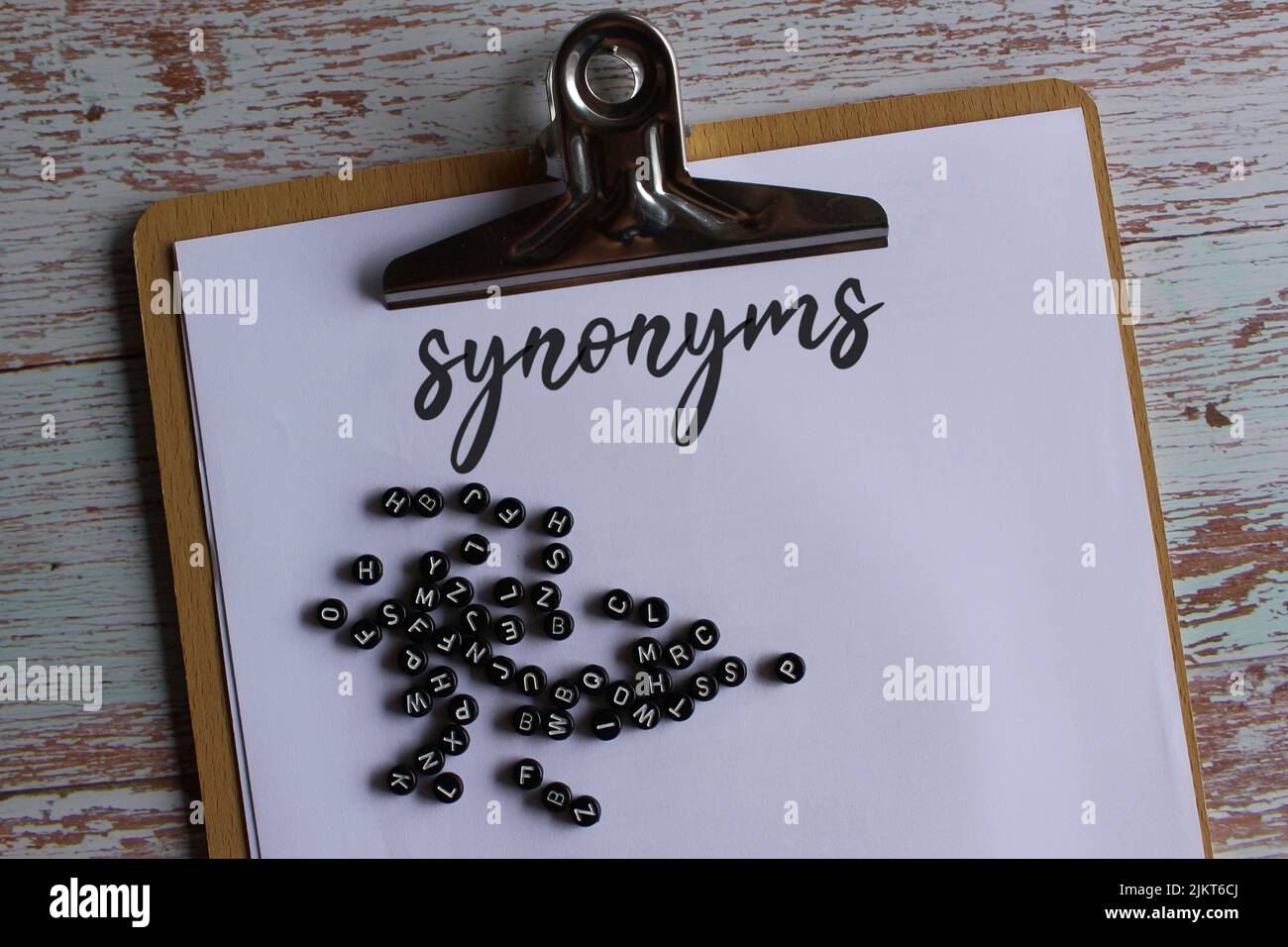 Bild von oben der Zwischenablage aus Papier mit Synonymen und Alphabetischen Perlen. Stockfoto