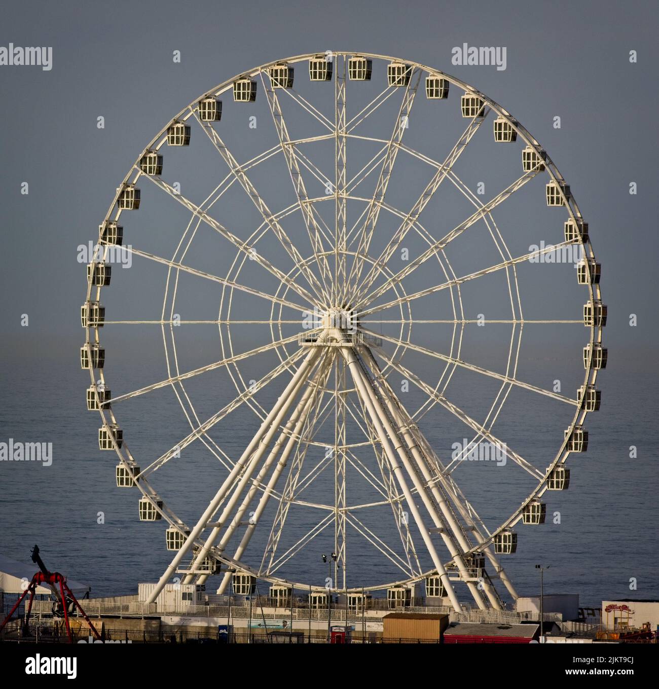 Eine Frontalaufnahme eines Riesenrads im Hintergrund einer Meereslandschaft. Stockfoto
