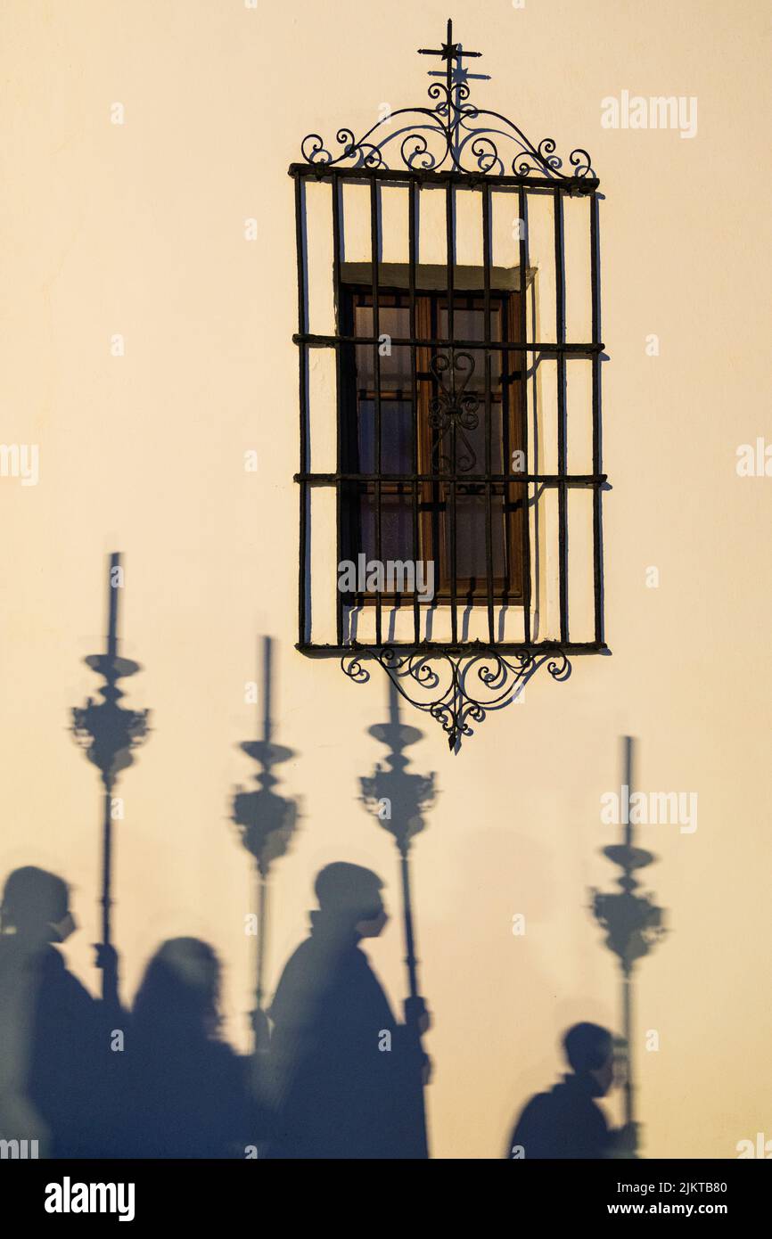 Eine schöne Aufnahme von Schatten der Menschen während des Semana Santa Andalucia Festivals auf der sonnigen Wand mit einem kleinen Fenster Stockfoto