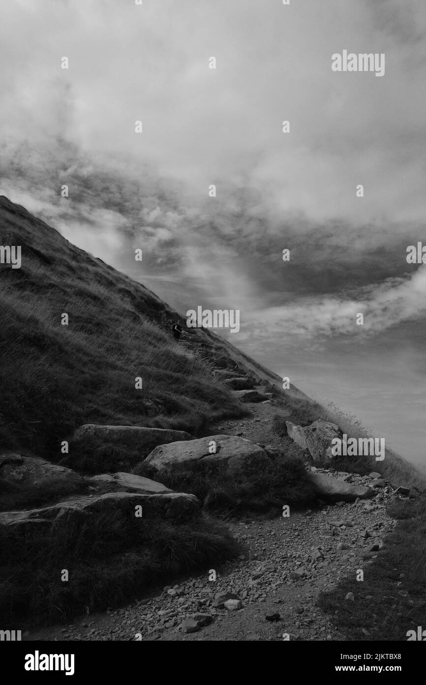 Eine Graustufe eines felsigen Hügels unter dem wolkigen Himmel Stockfoto