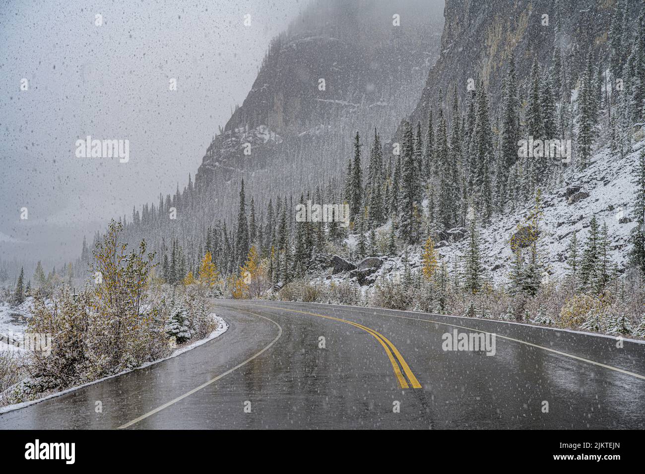 Die leere Straße, die im Winter an der Bergkette vorbeiführt. Kanadische Natur. Stockfoto