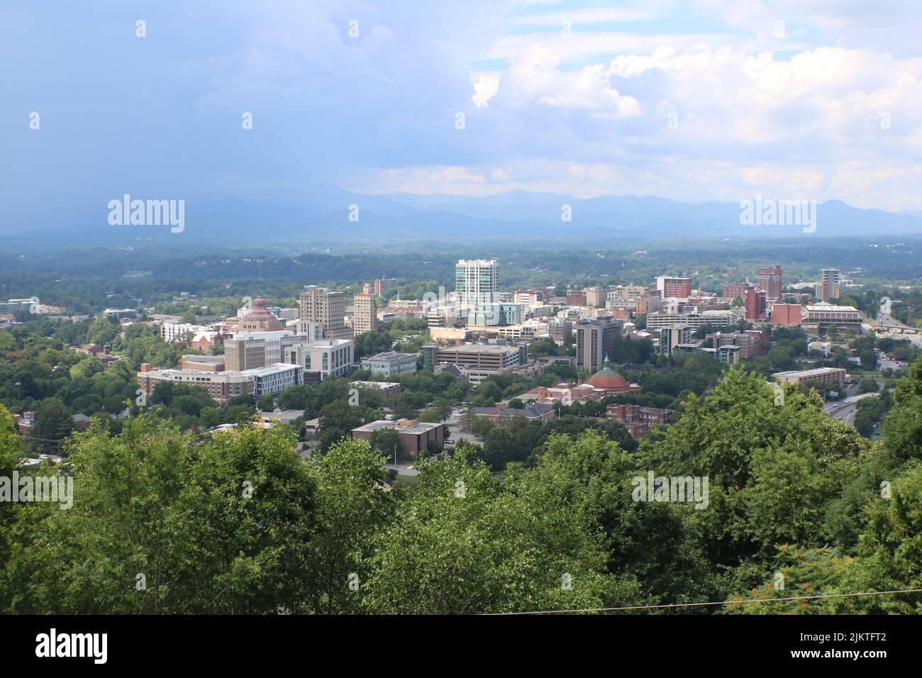 Eine wunderschöne Aussicht auf die Stadt mit hohen Gebäuden und grünen Bäumen vor einem bewölkten Himmel Stockfoto