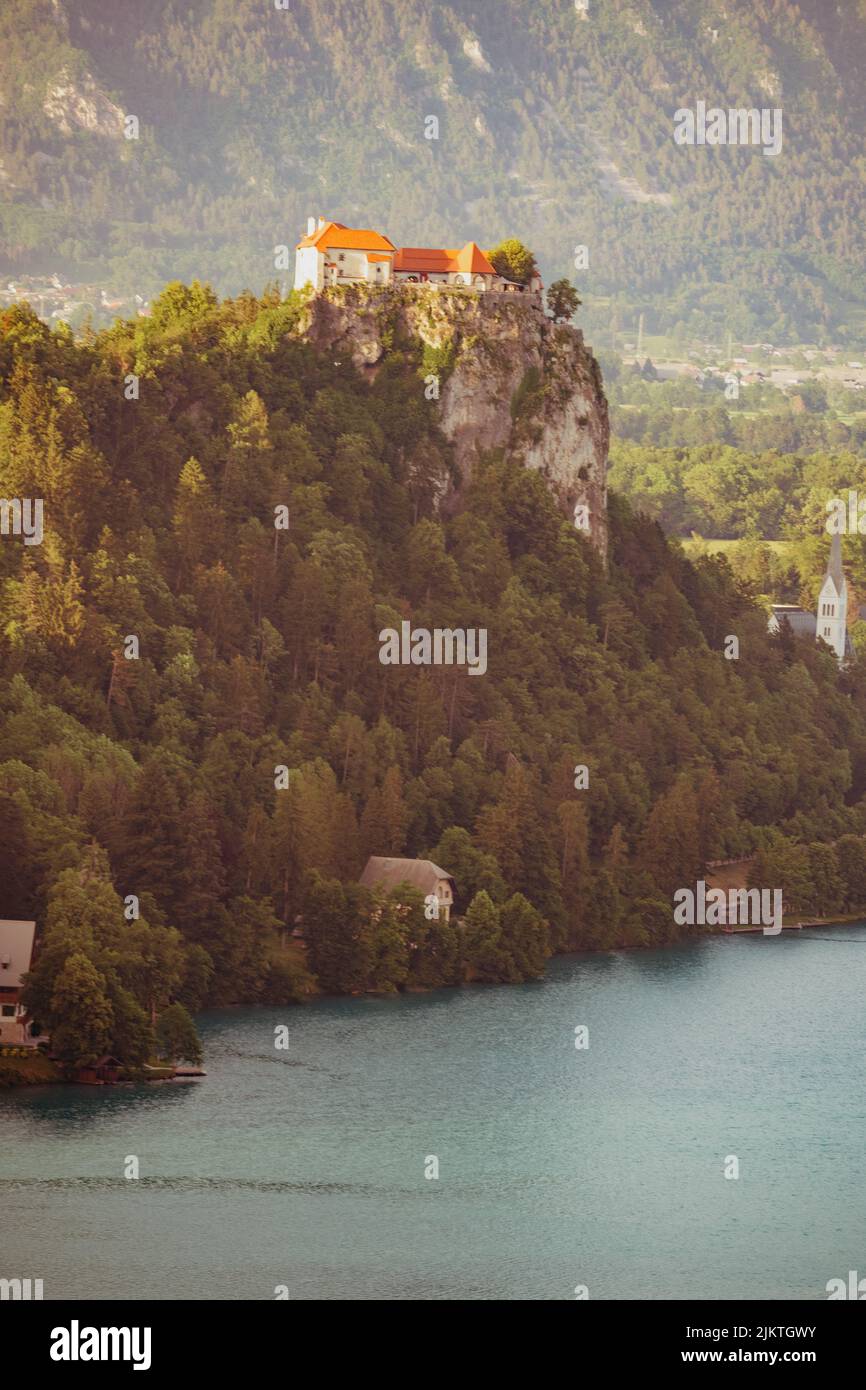 Eine vertikale Aufnahme von einigen Häusern, die auf einer Klippe, umgeben von Bäumen, im Hintergrund von Bergen aufgestellt sind. Stockfoto
