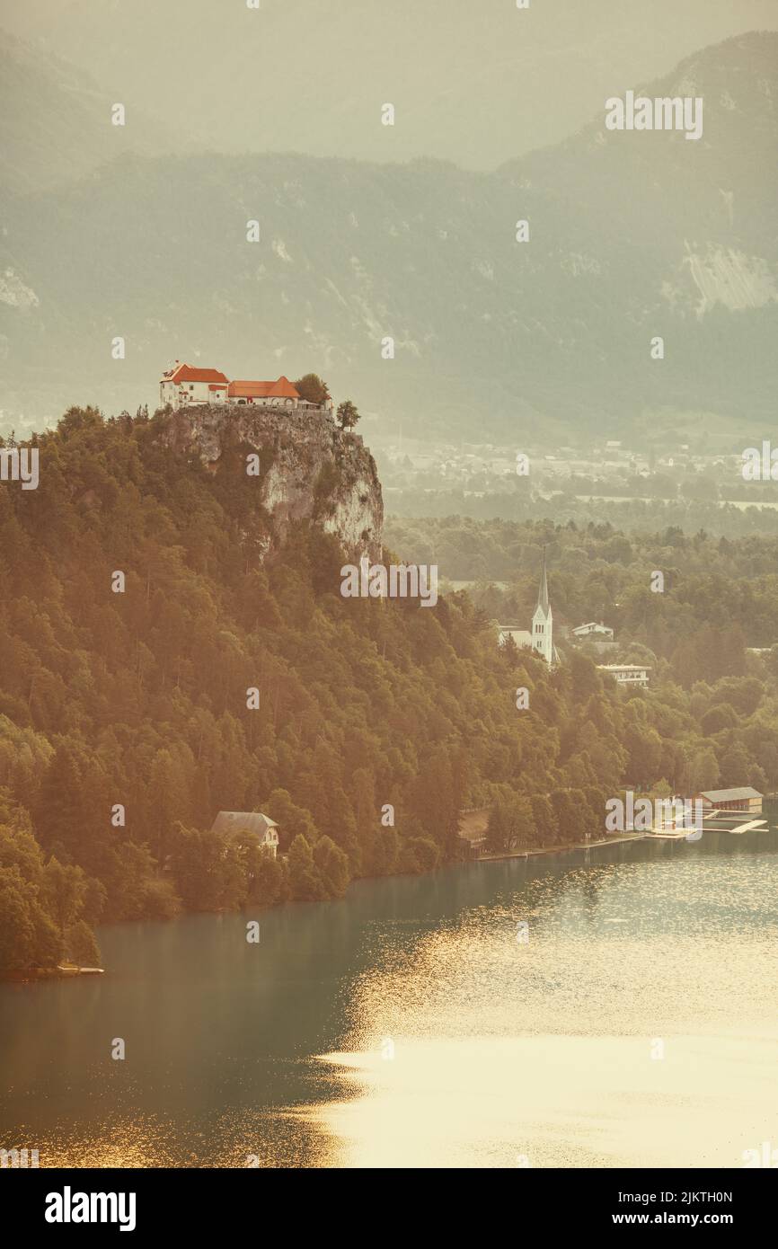 Eine vertikale Aufnahme von einigen Häusern, die auf einer Klippe, umgeben von Bäumen, im Hintergrund von Bergen aufgestellt sind. Stockfoto