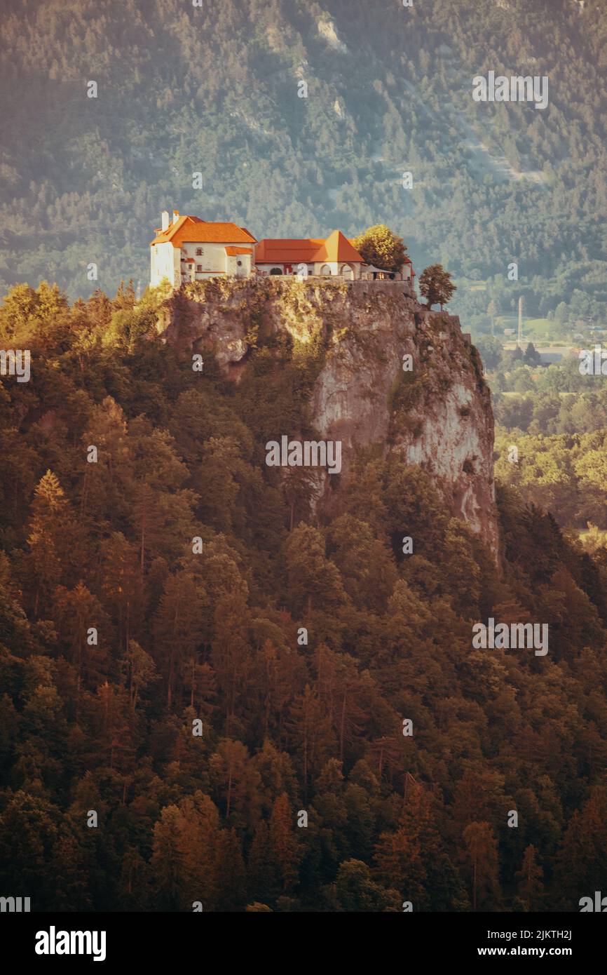 Eine vertikale Aufnahme von einigen Häusern, die auf einer Klippe, umgeben von Bäumen, im Hintergrund von Bergen aufgestellt sind. Stockfoto