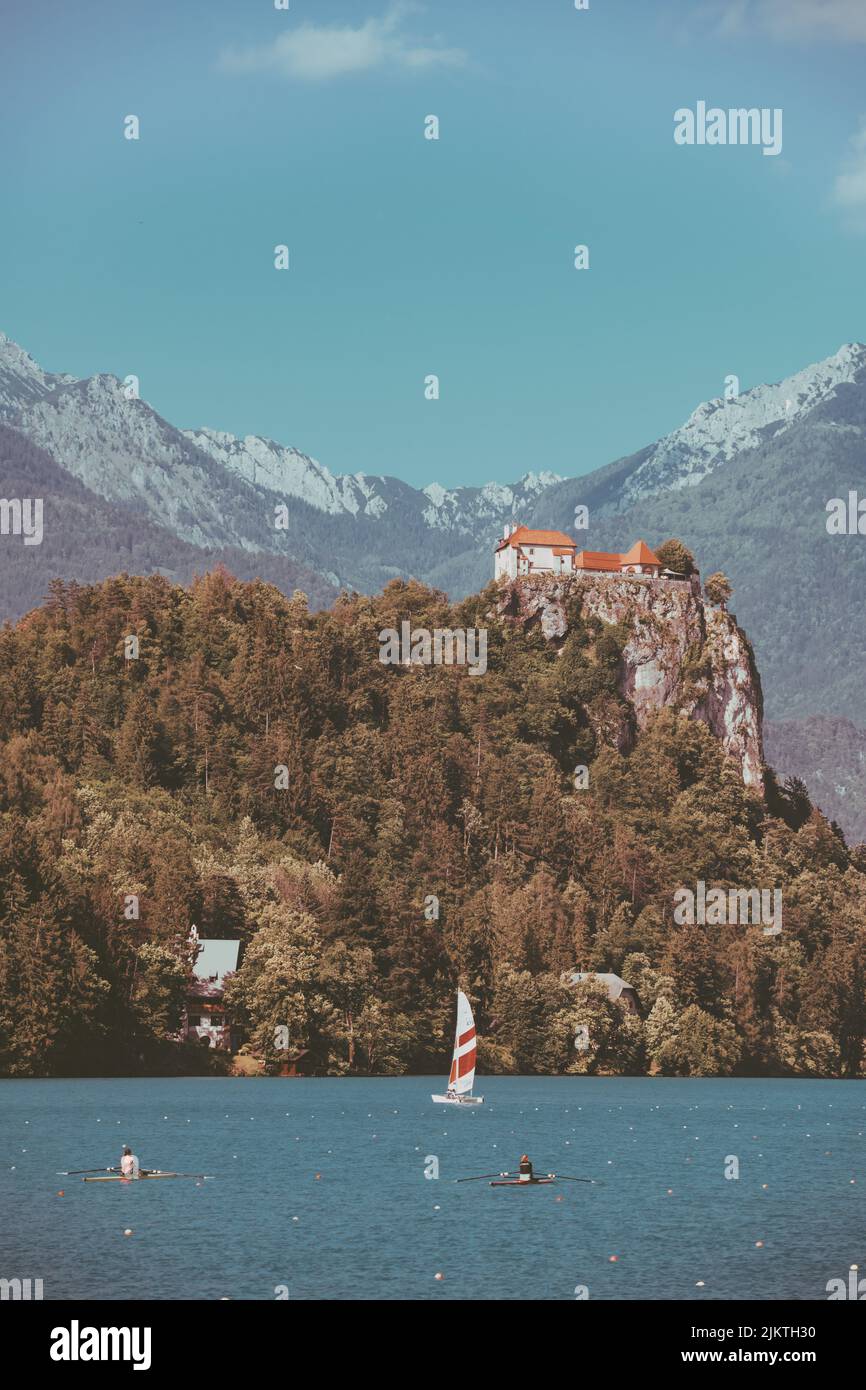 Eine vertikale Aufnahme von einigen Häusern, die auf einer Klippe, umgeben von Bäumen, im Hintergrund von Bergen aufgestellt sind. Stockfoto