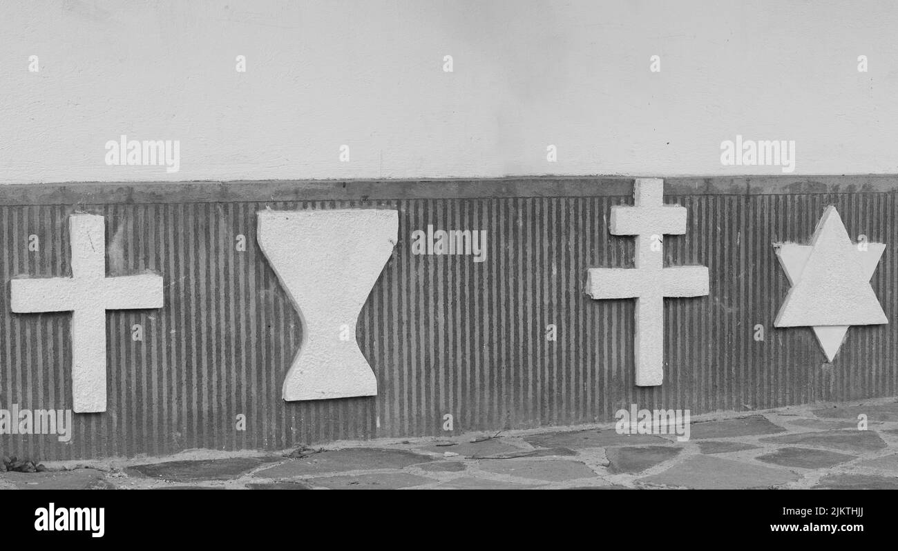 Die Insignien mehrerer religiöser Kulte an einer alten Mauer Stockfoto