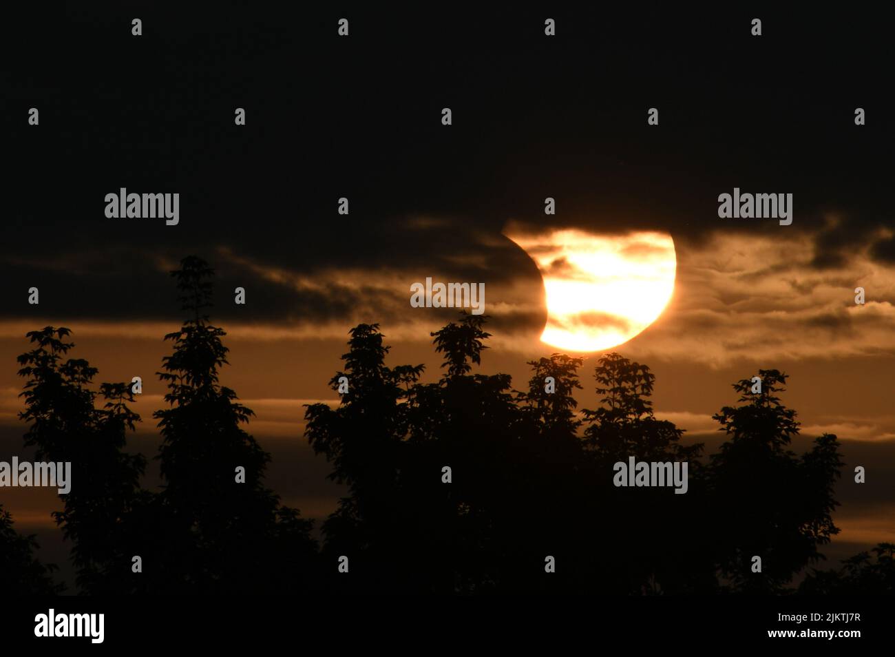 Ein schöner Blick auf die partielle Sonnenfinsternis mit Wolken und Bäumen Stockfoto