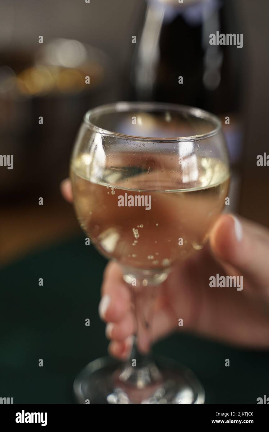 Eine Nahaufnahme einer Hand, die ein Glas Weißwein hält Stockfoto
