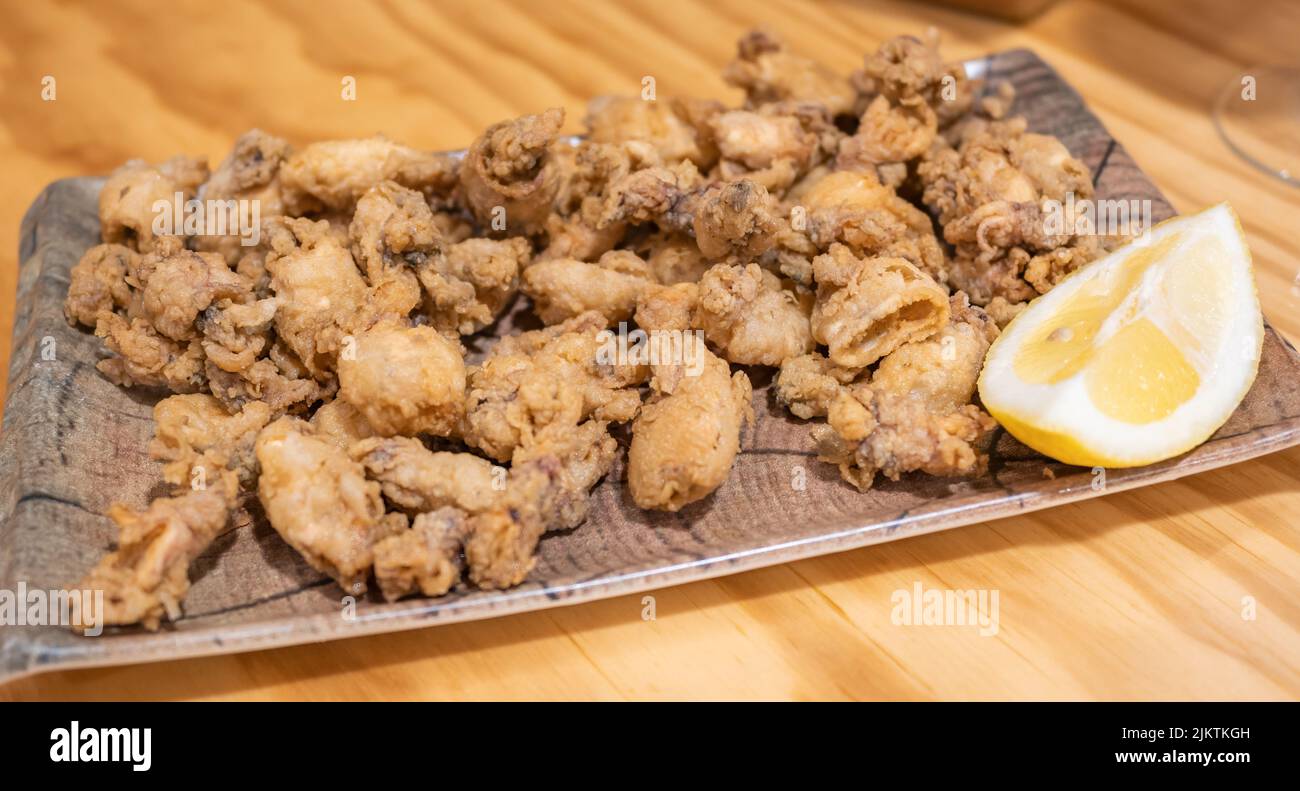 Deliciosa ración de chopitos o puntillas Fritas y crujientes con Limón Stockfoto