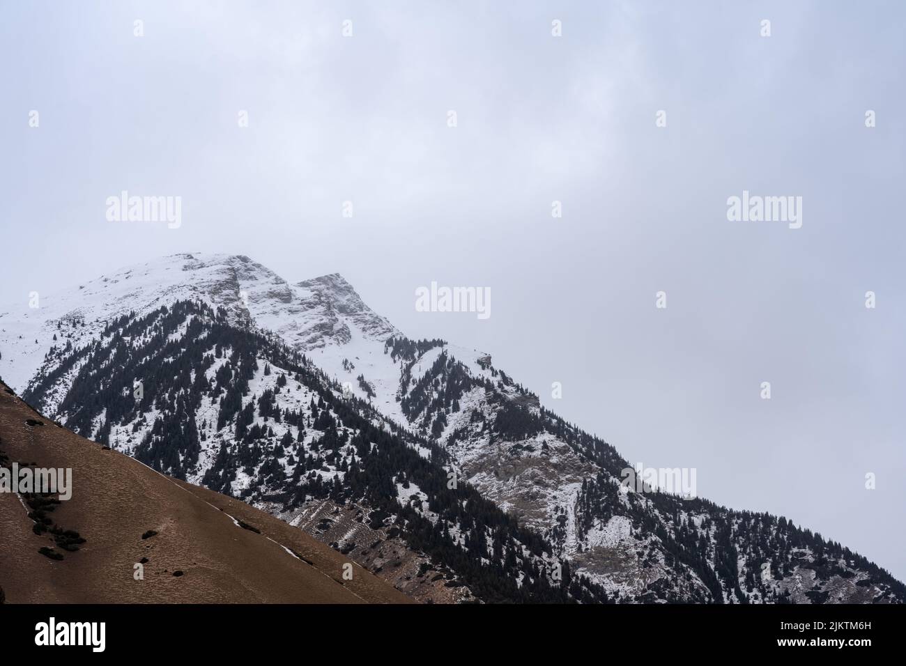 Die schöne Aussicht auf den verschneiten Berggipfel gegen den bewölkten Himmel. Stockfoto
