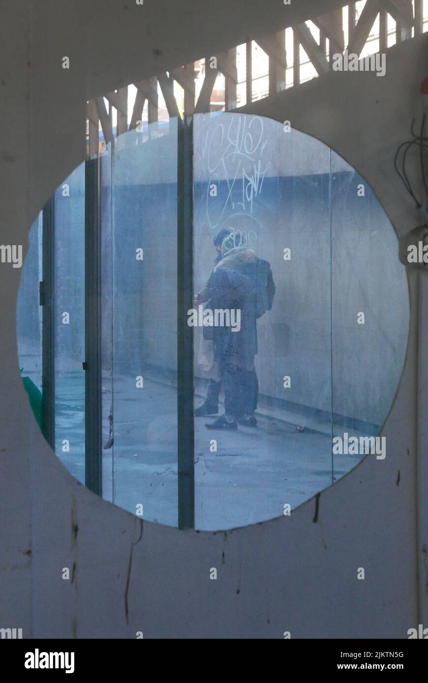 Ein Blick auf zwei Männer, die durch ein rundes Fenster in der Holzwand rauchten Stockfoto