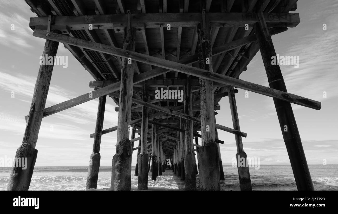 Eine Graustufenaufnahme von hölzernen Pier-Stützen in Newport Beach Stockfoto