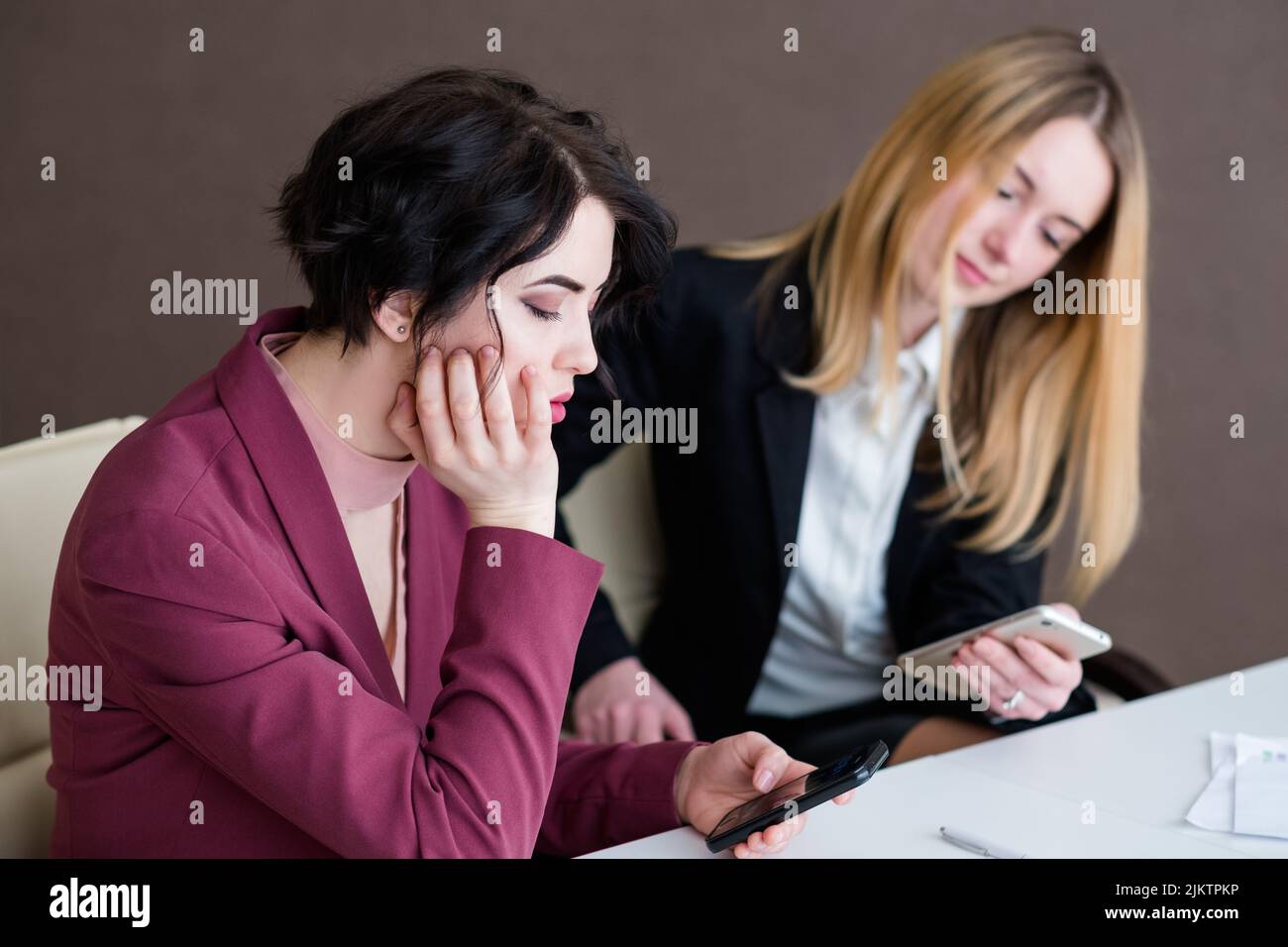 Gelangweilte Geschäftsfrauen im Büro, die nicht so gerne telefonieren Stockfoto